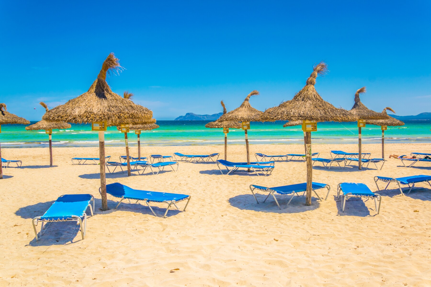 Blaue Sonnenliegen und Sonnenschirmen am Playa de Muro