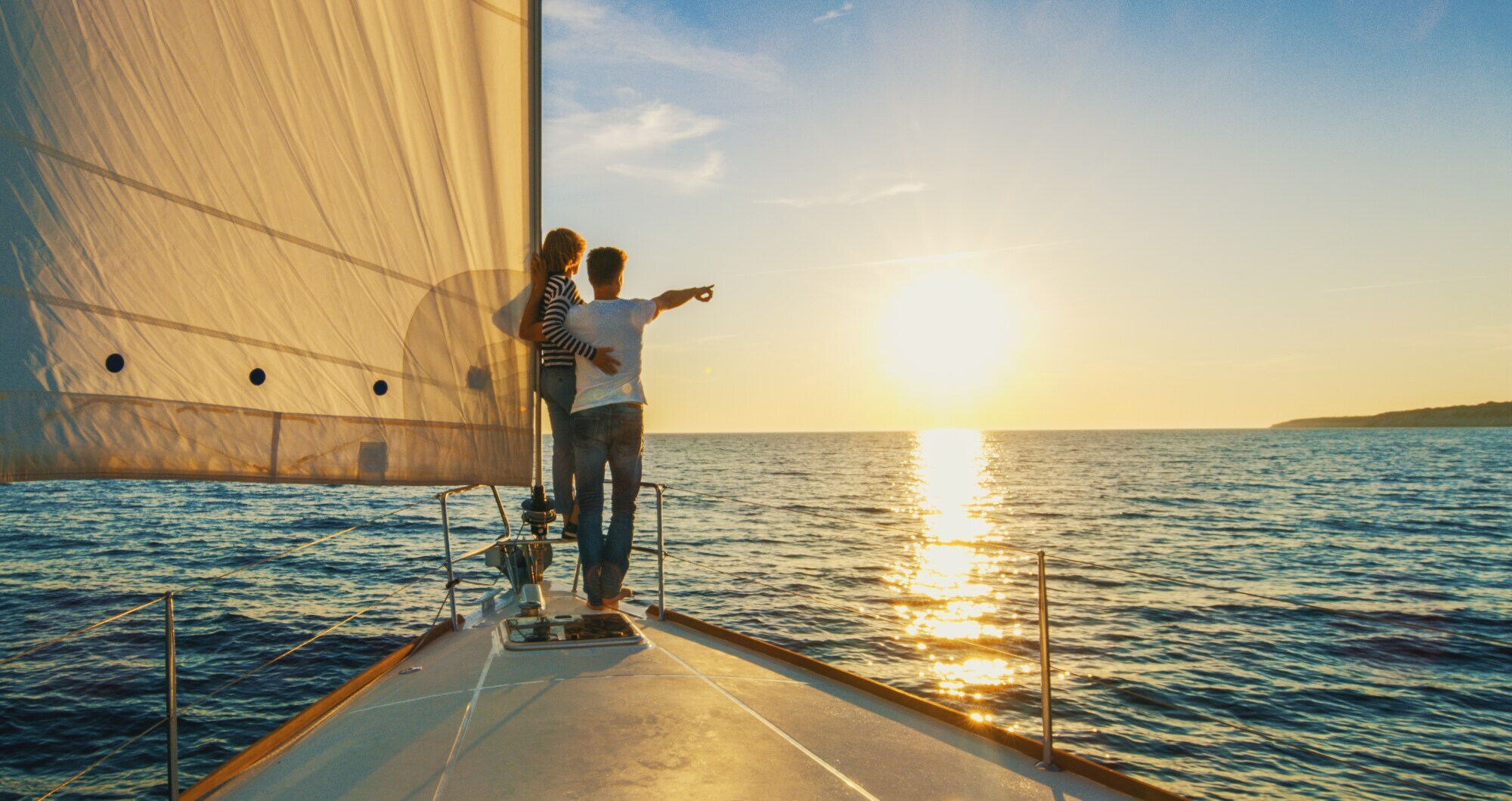 Ein Paar schaut sich auf einem Segelboot den Sonnenuntergang an