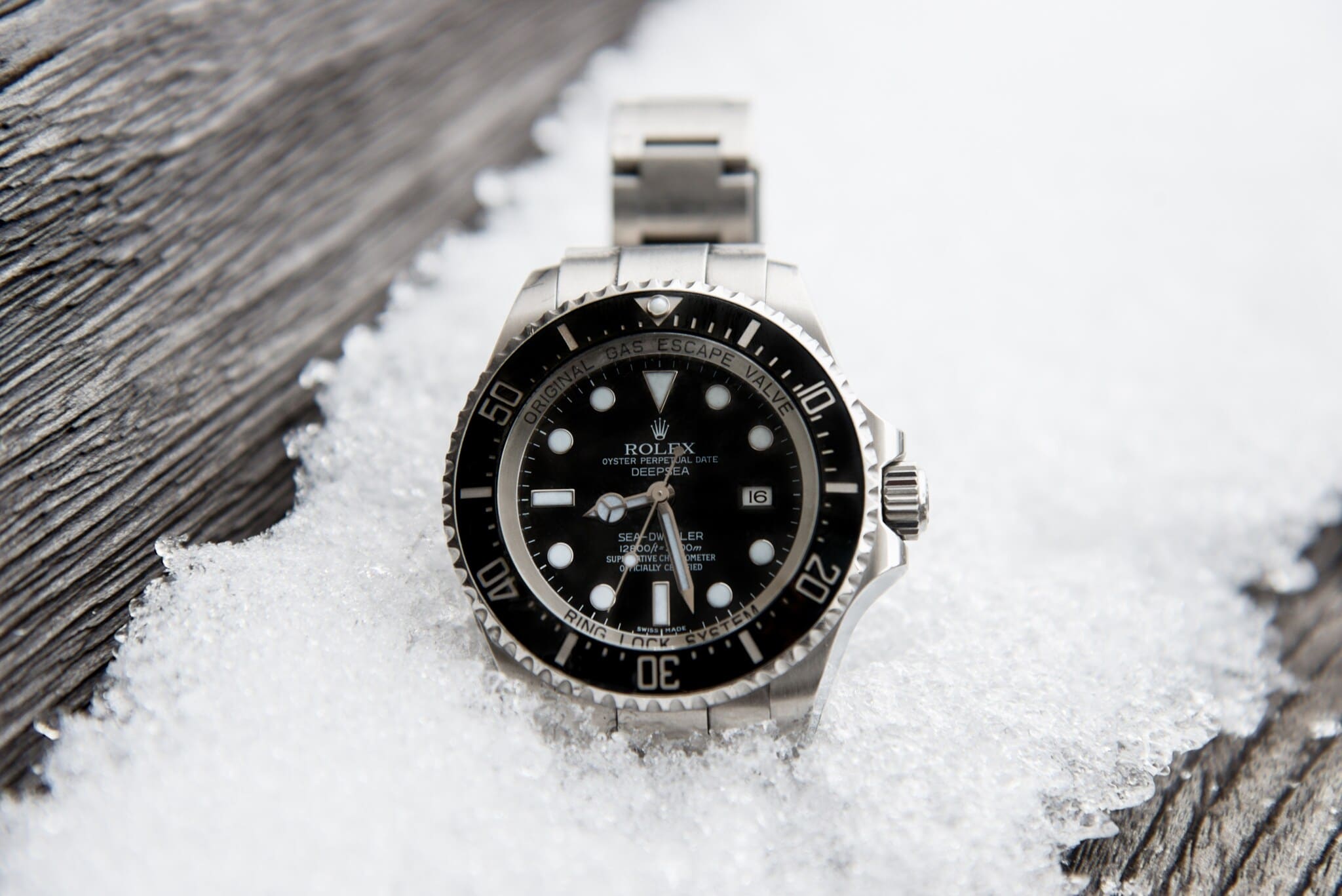 Rolex Oyster Perpetual Deepsea vor vereistem Schnee auf einem Holzbrett Rolex Oyster Perpetual Deepsea vor vereistem Schnee auf einem Holzbrett