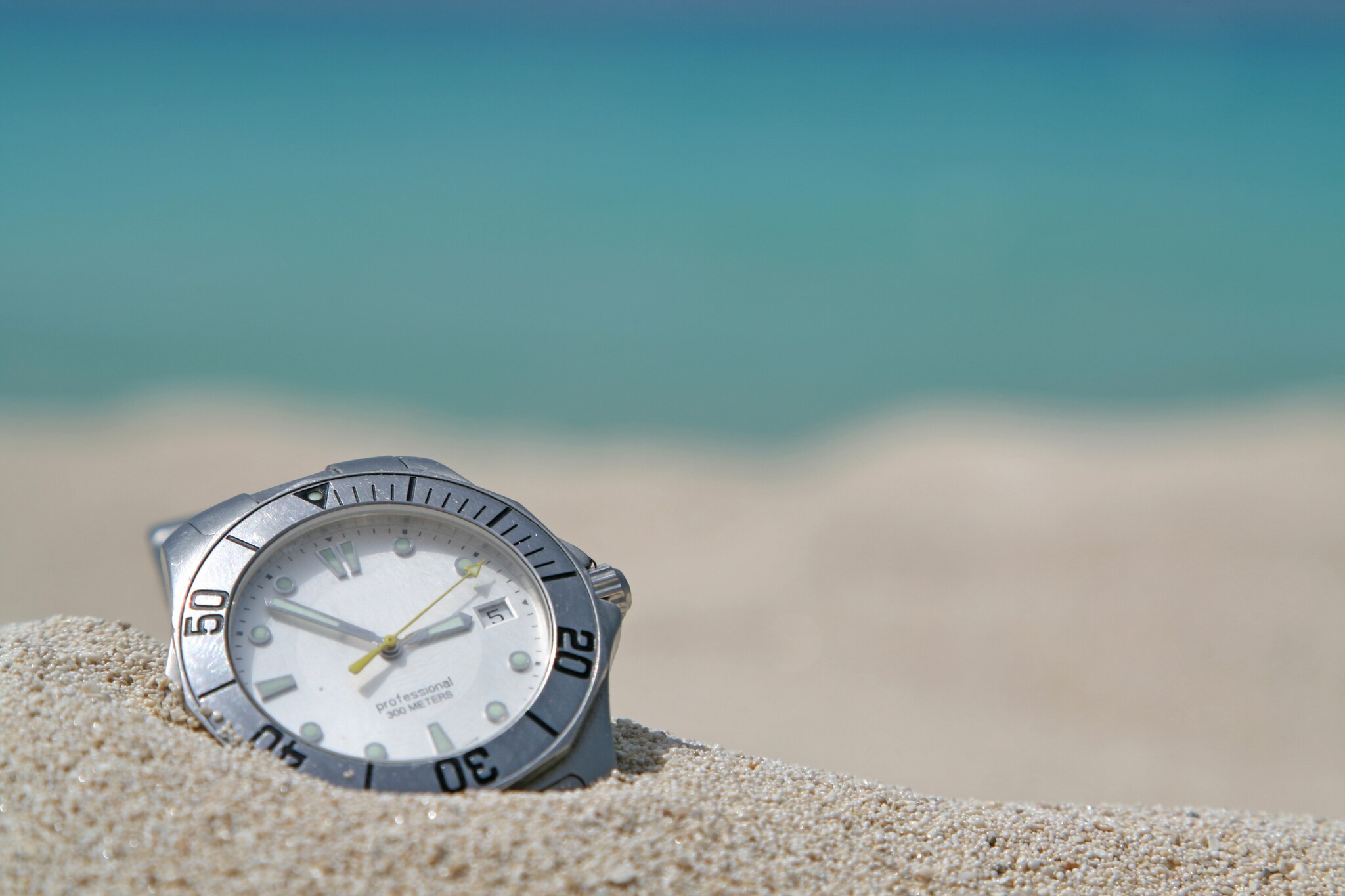 Taucheruhr mit Stahlgehäuse und weißem Zifferblatt in hellem Sand