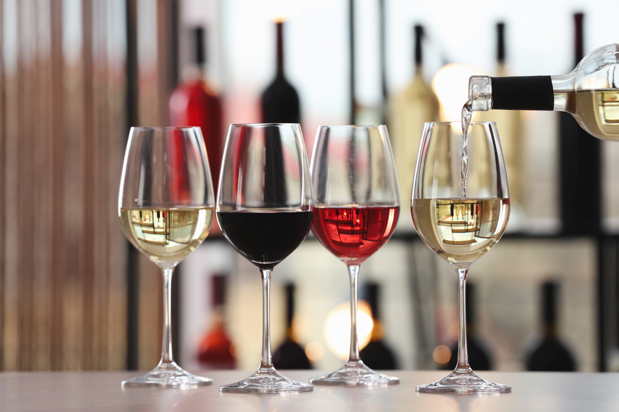 Vier Gläser nebeneinander, gefüllt mit Rot- und Weißwein sowie Rosé