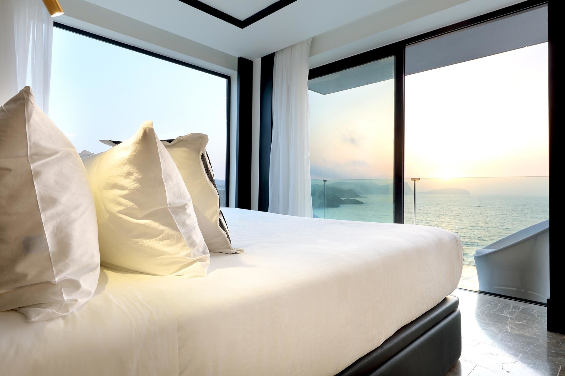 Ein Bett in einem Hotelzimmer mit Blick auf das Meer und den Sonnenuntergang Ein Bett in einem Hotelzimmer mit Blick auf das Meer und den Sonnenuntergang