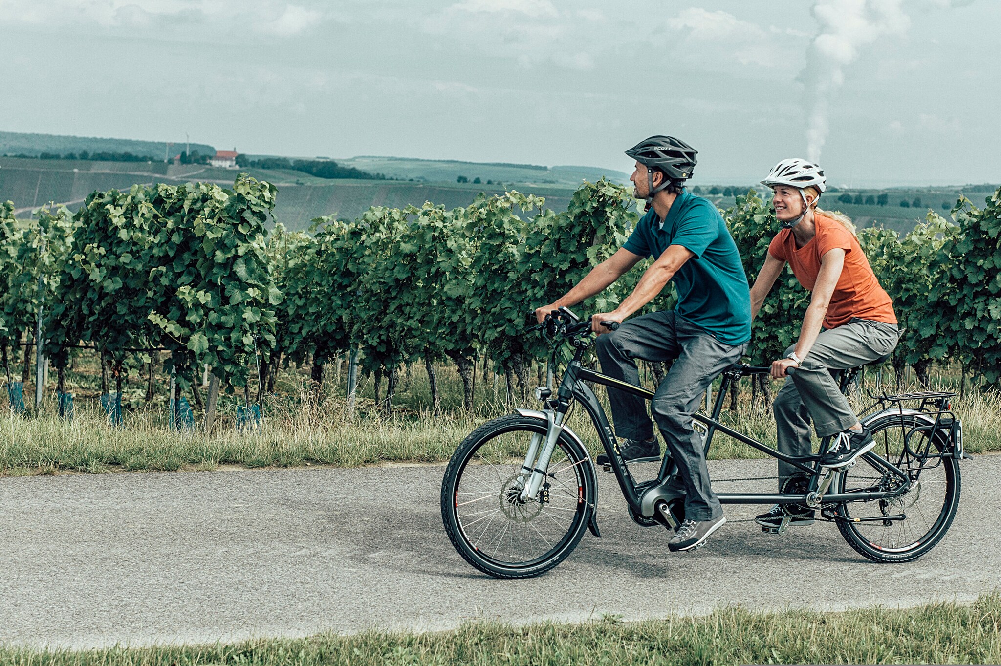 Ein Paar auf einem Tandem an einem Weinberg Ein Paar auf einem Tandem an einem Weinberg