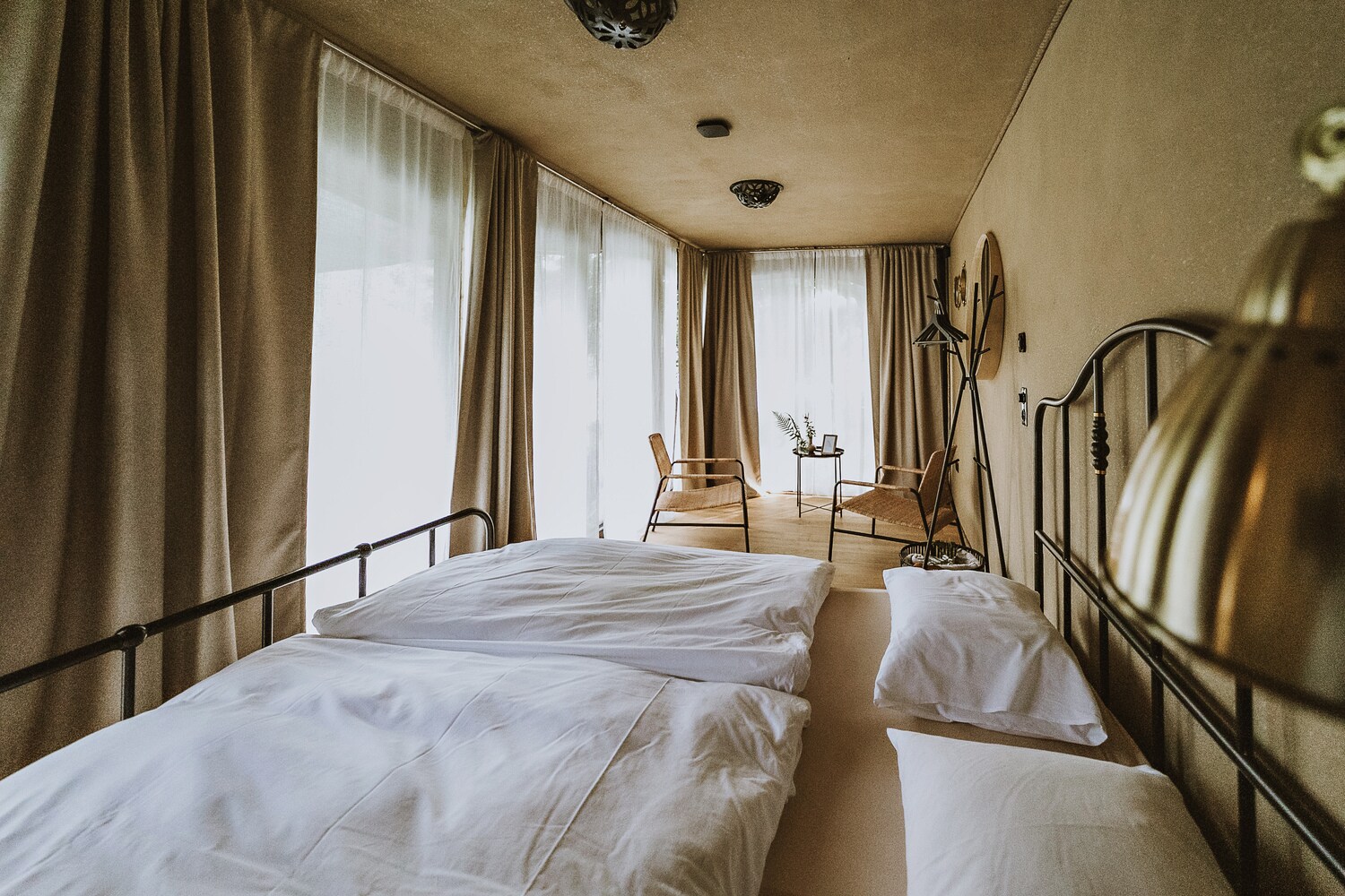 Blick in ein Hotelzimmer mit Doppelbett und zwei Stühlen.