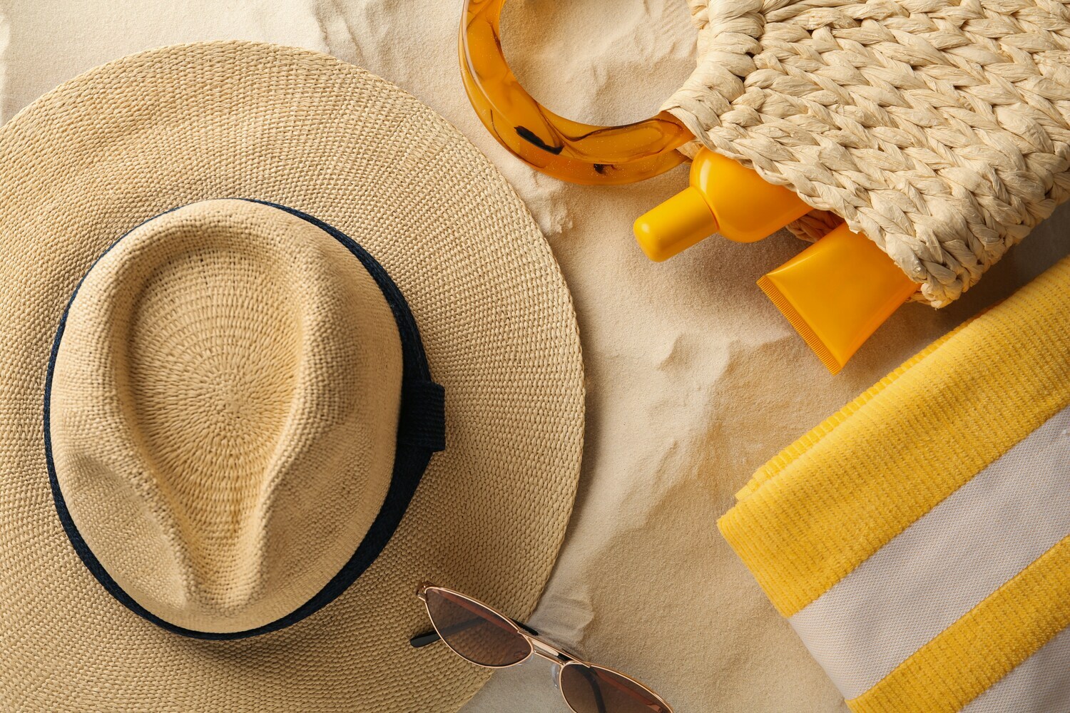 Stillleben mit Strohhut und Sommer-Accessoires im Sand
