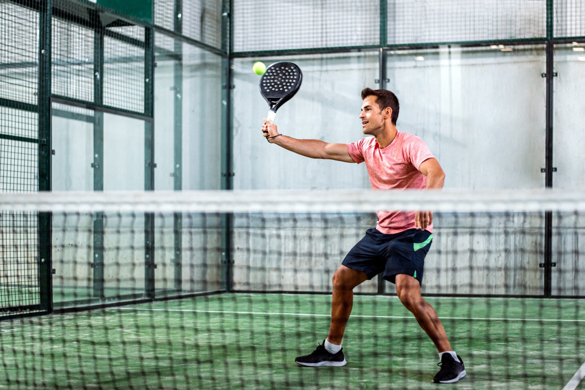 Ein Mann spielt Padel-Tennis in der Halle.