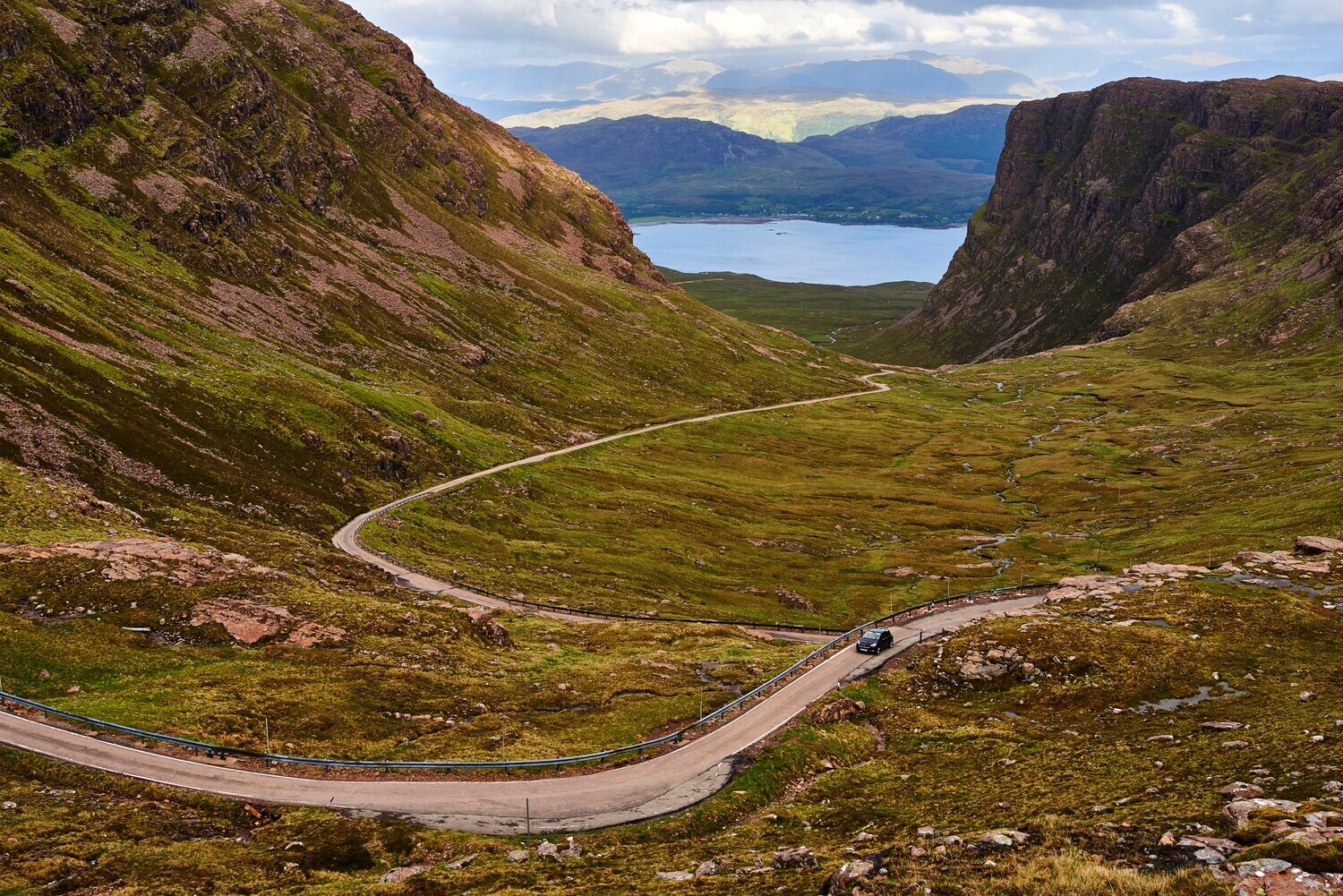 Ein Auto auf einer einsamen Straße zwischen Bergen Ein Auto auf einer einsamen Straße zwischen Bergen