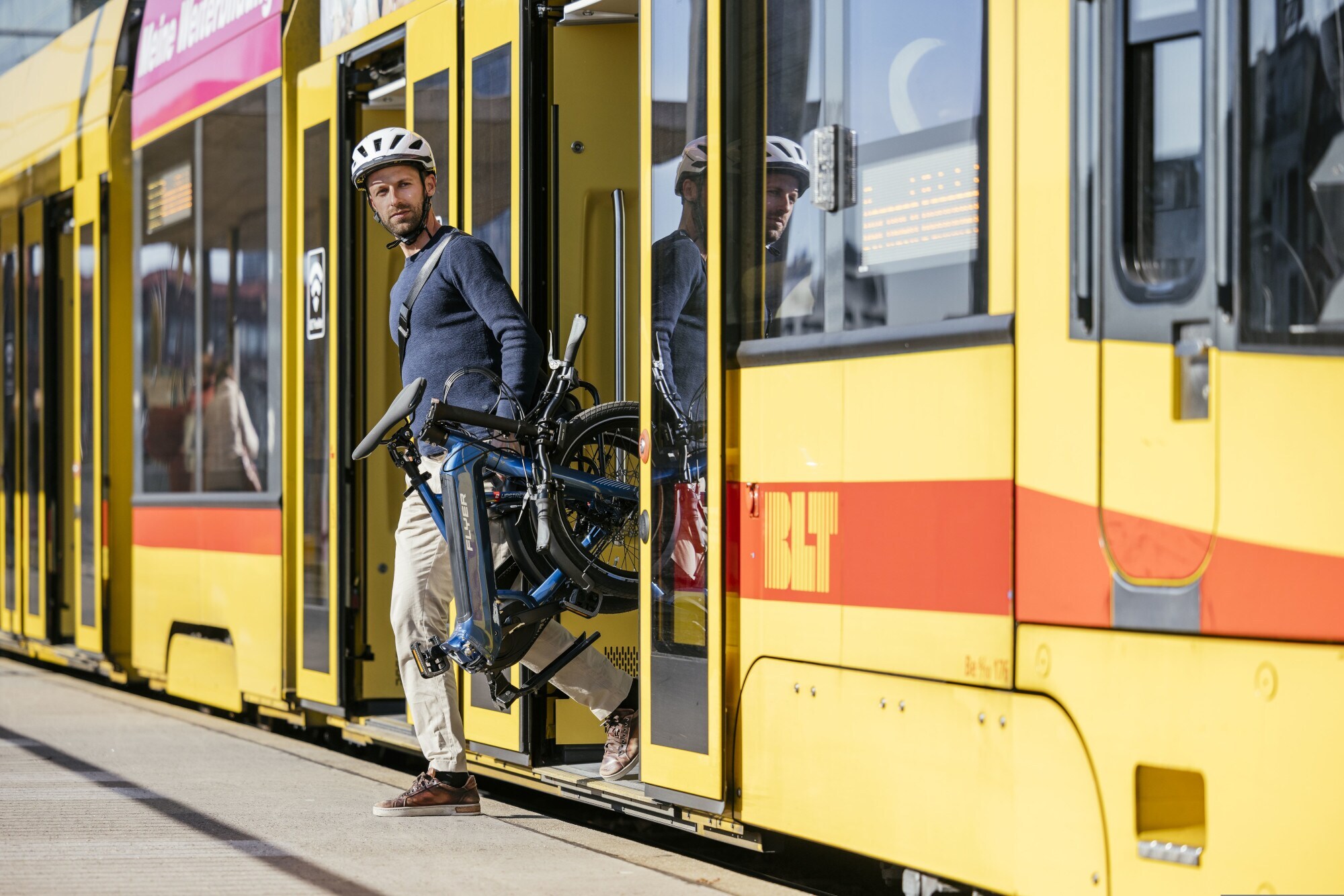 Ein Mann steigt mit einem Klapprad aus einer Tram