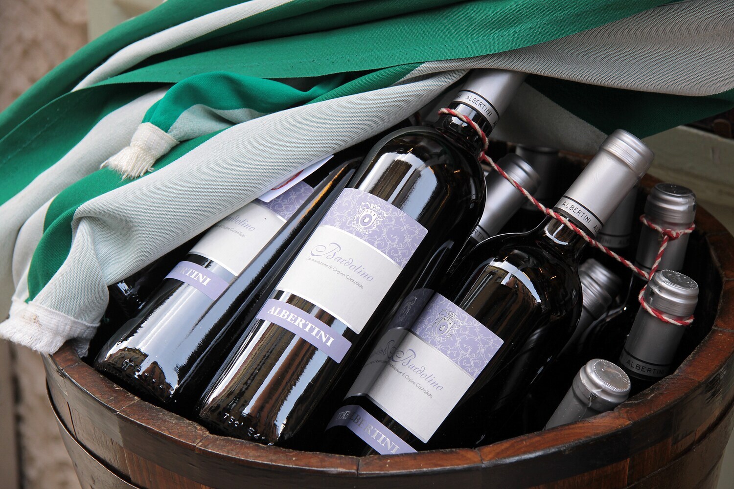 Rotweinflaschen in einem Holzfass, das halb mit einem Tuch abgedeckt ist