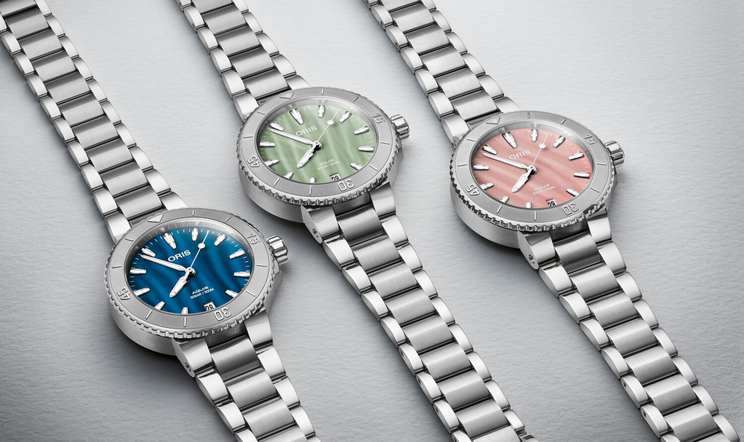 Drei silberne Uhren mit verschiedenfarbigen Ziffernblättern liegen nebeneinander