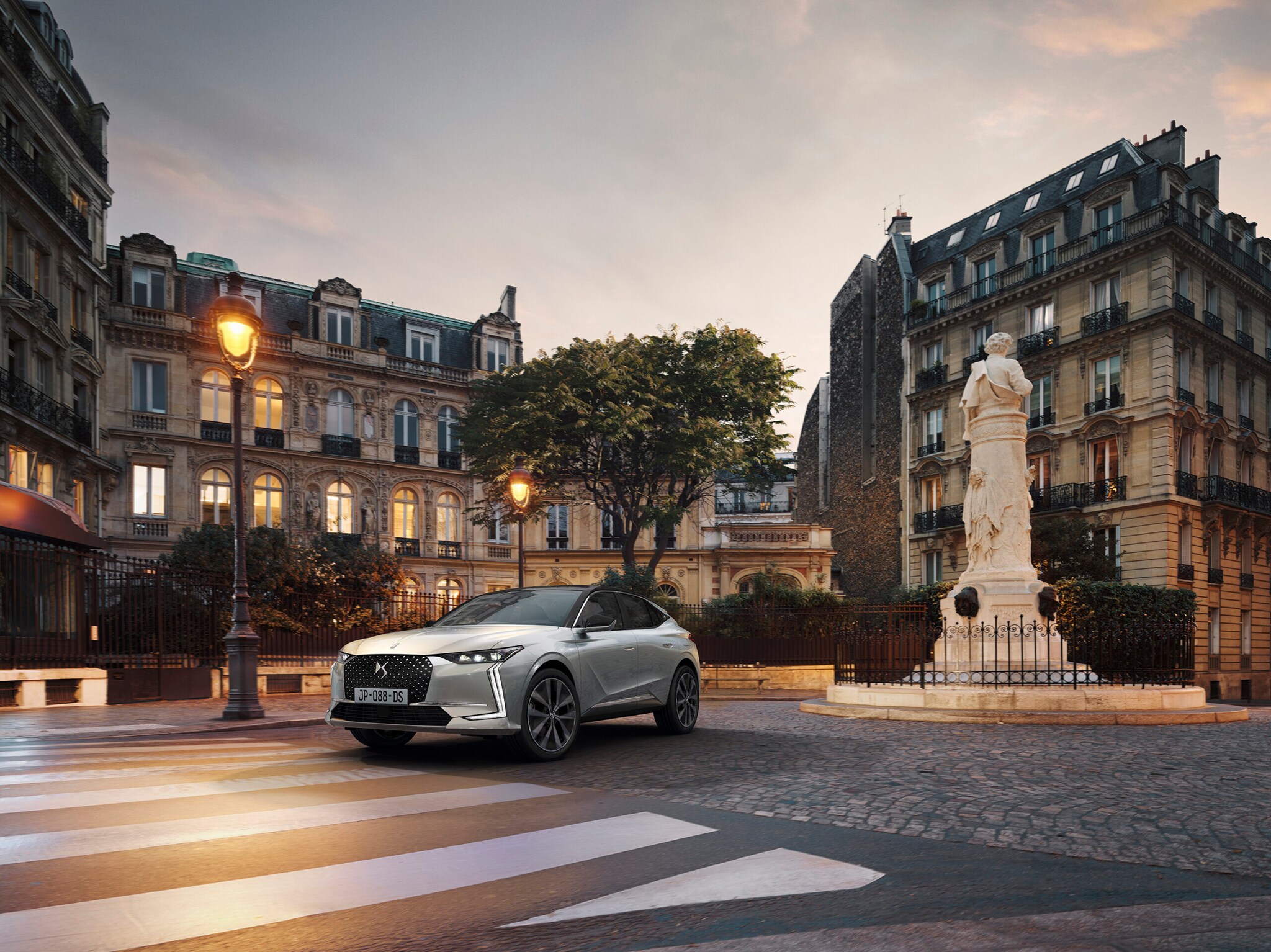 Ein weißes Auto auf einem Platz in der Stadt vor einem Zebrastreifen