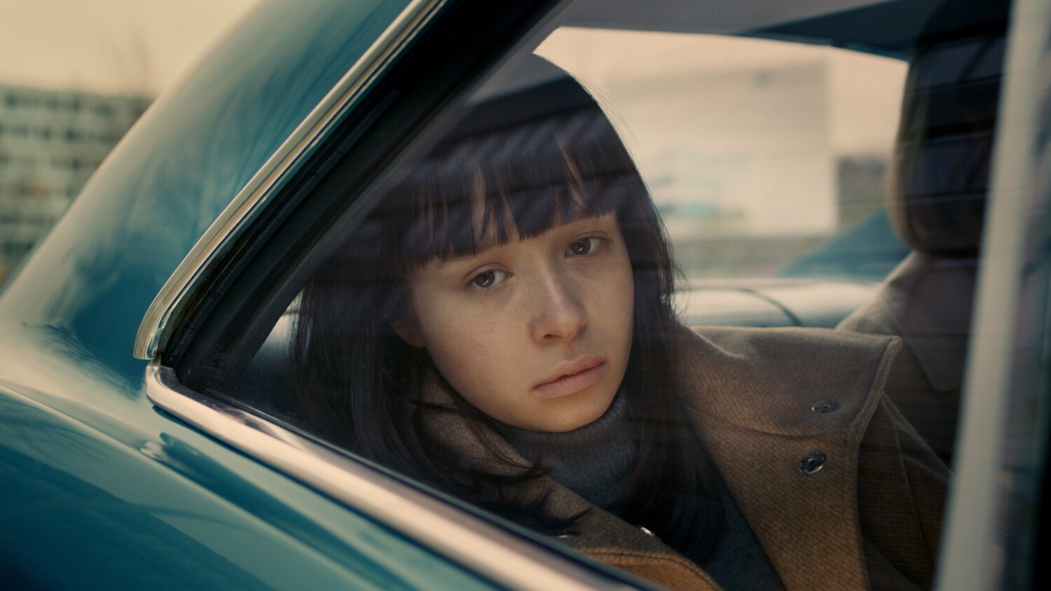 Filmszene aus dem Film The Ordinaries, in der ein Mädchen aus einem Autofenster schaut