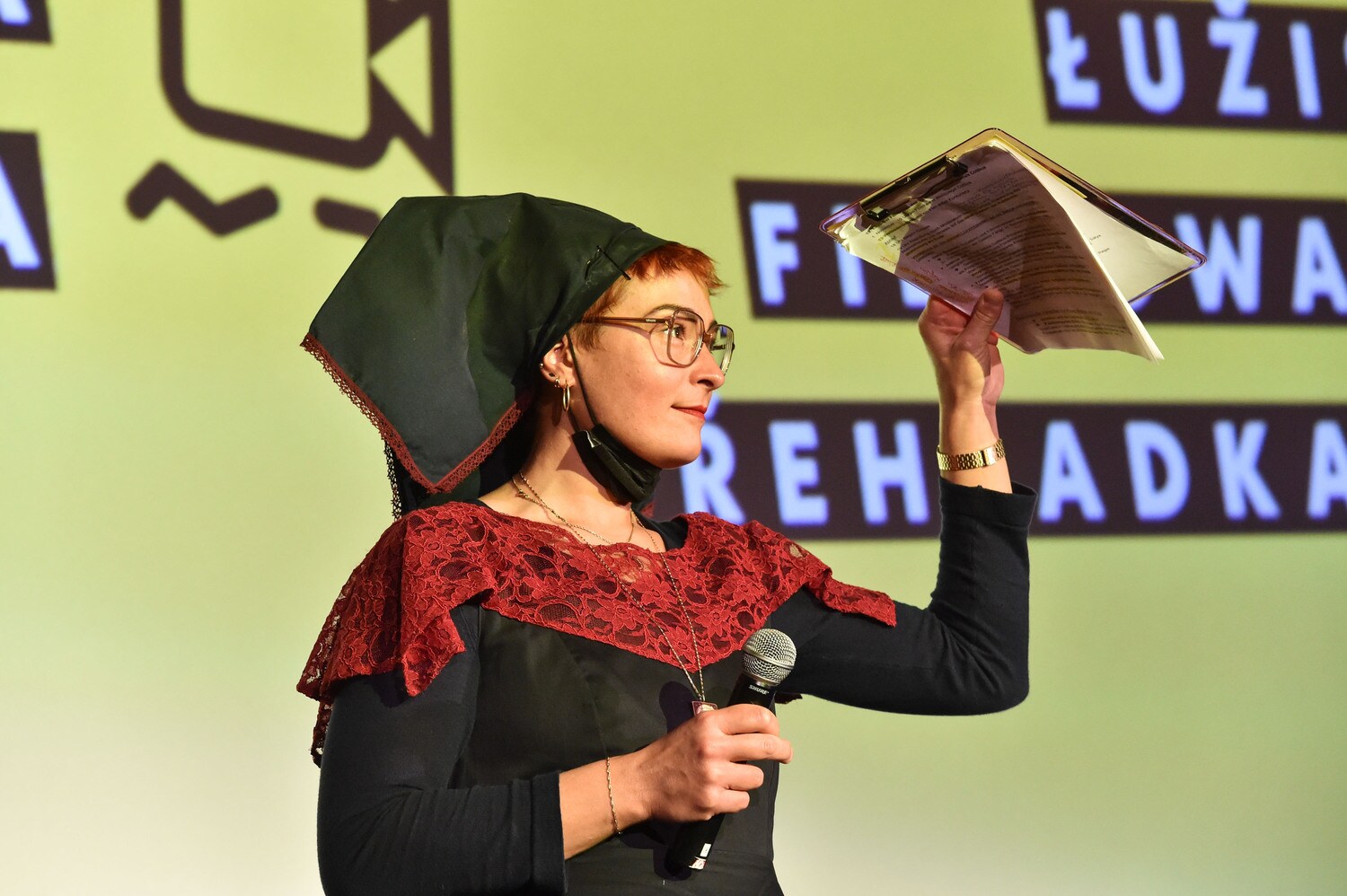 Eine junge Frau in sorbischer Tracht auf einer Bühne mit Mikrofon beim Filmfestival Cottbus