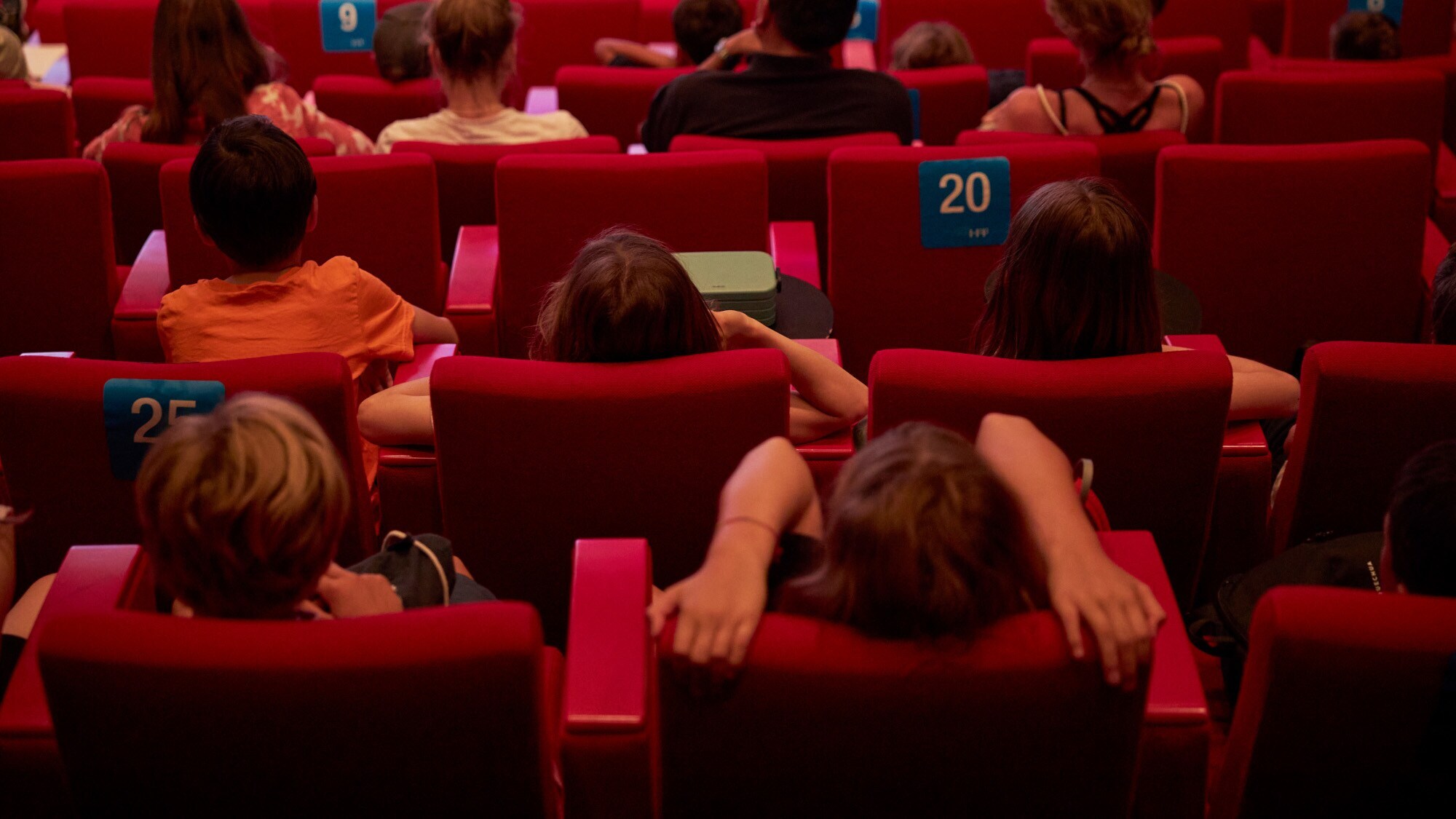 Rückansicht von Kindern in roten Kinosesseln