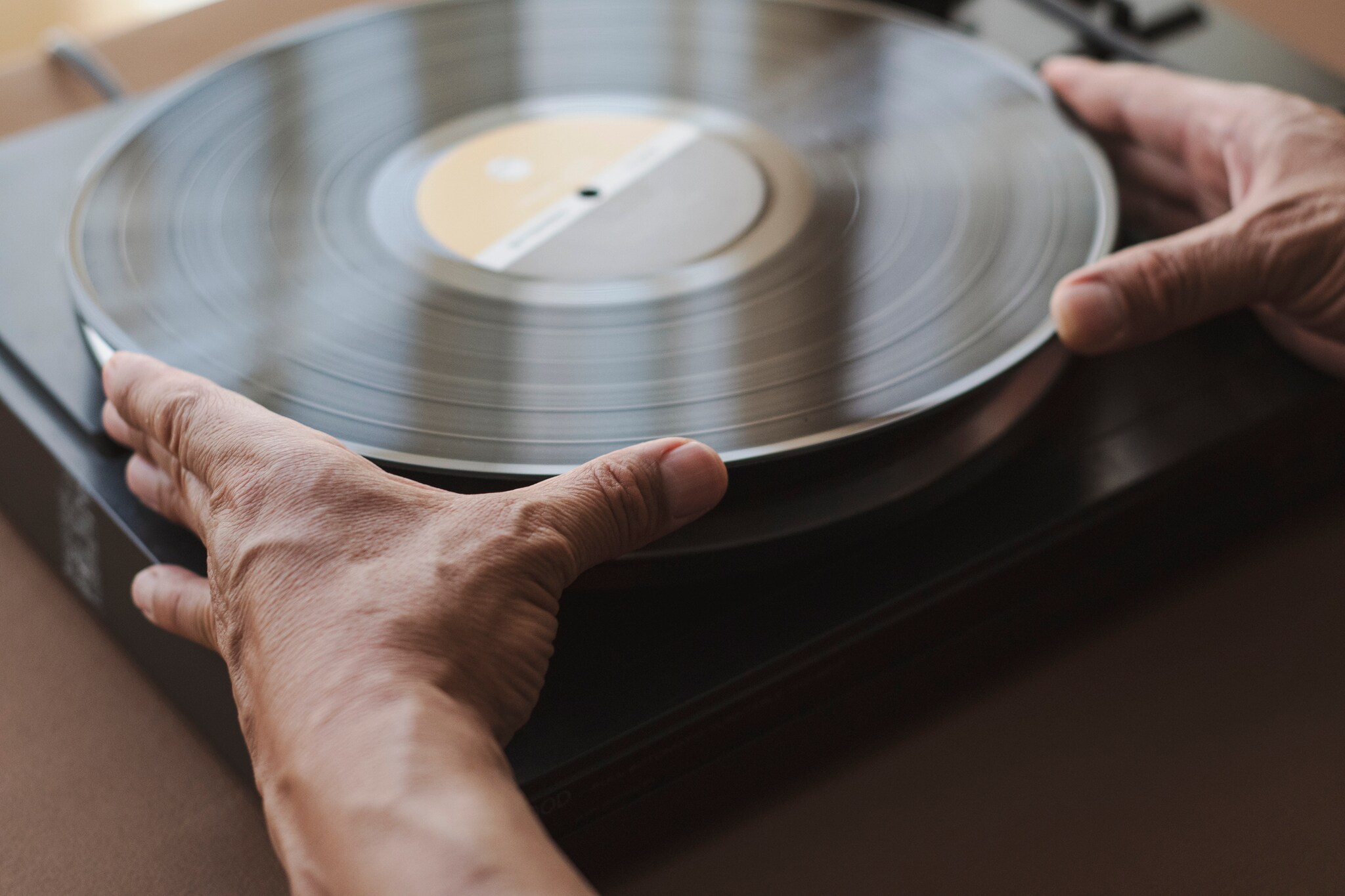 Zwei Hände, die das Vinyl auf dem Plattenteller aufnehmen