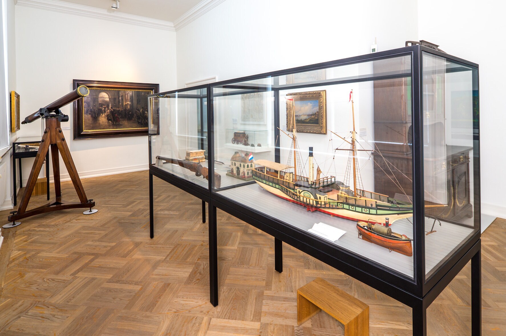 Innenansicht eines Museumsraumes mit einem alten Teleskop und einer Vitrine