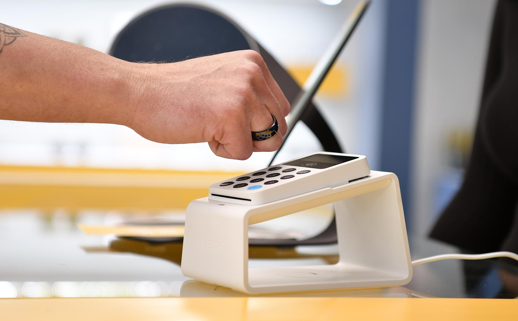 Eine Hand mit dunklem NFC-Ring beim kontaktlosen Bezahlen Eine Hand mit dunklem NFC-Ring beim kontaktlosen Bezahlen