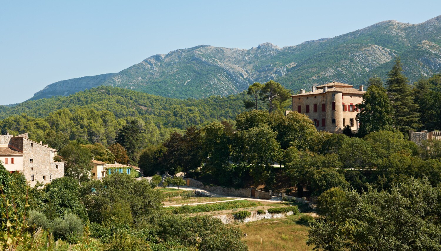 Das bewaldete Anwesen rund um Schloss Vauvenargues vor einem Gebirgszug