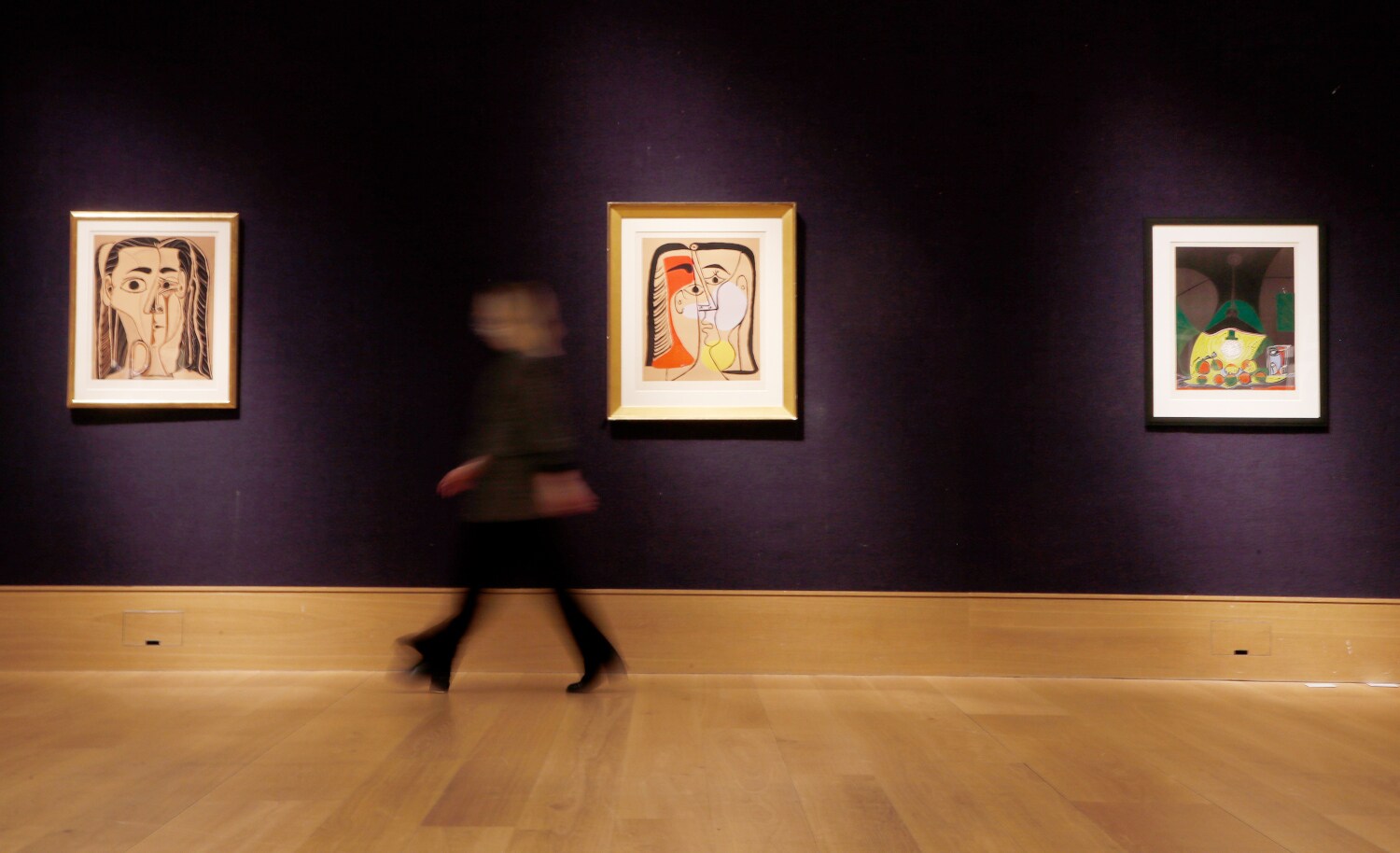 Eine Person geht in einem Ausstellungsraum an einer Wand mit drei Linolschnitten von Picasso vorbei Eine Person geht in einem Ausstellungsraum an einer Wand mit drei Linolschnitten von Picasso vorbei