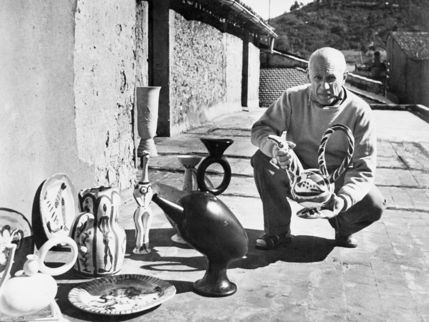 Schwarzweißfoto von Pablo Picasso mit Keramikarbeiten vor seinem Studio in Vallauris Schwarzweißfoto von Pablo Picasso mit Keramikarbeiten vor seinem Studio in Vallauris