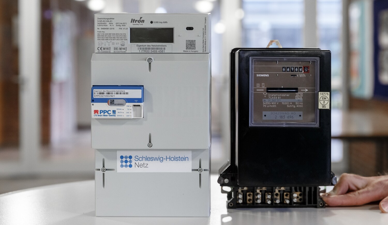 Ein digitaler Stromzähler mit Smart-Meter-Gateway steht neben einem herkömmlichen analogen Zähler