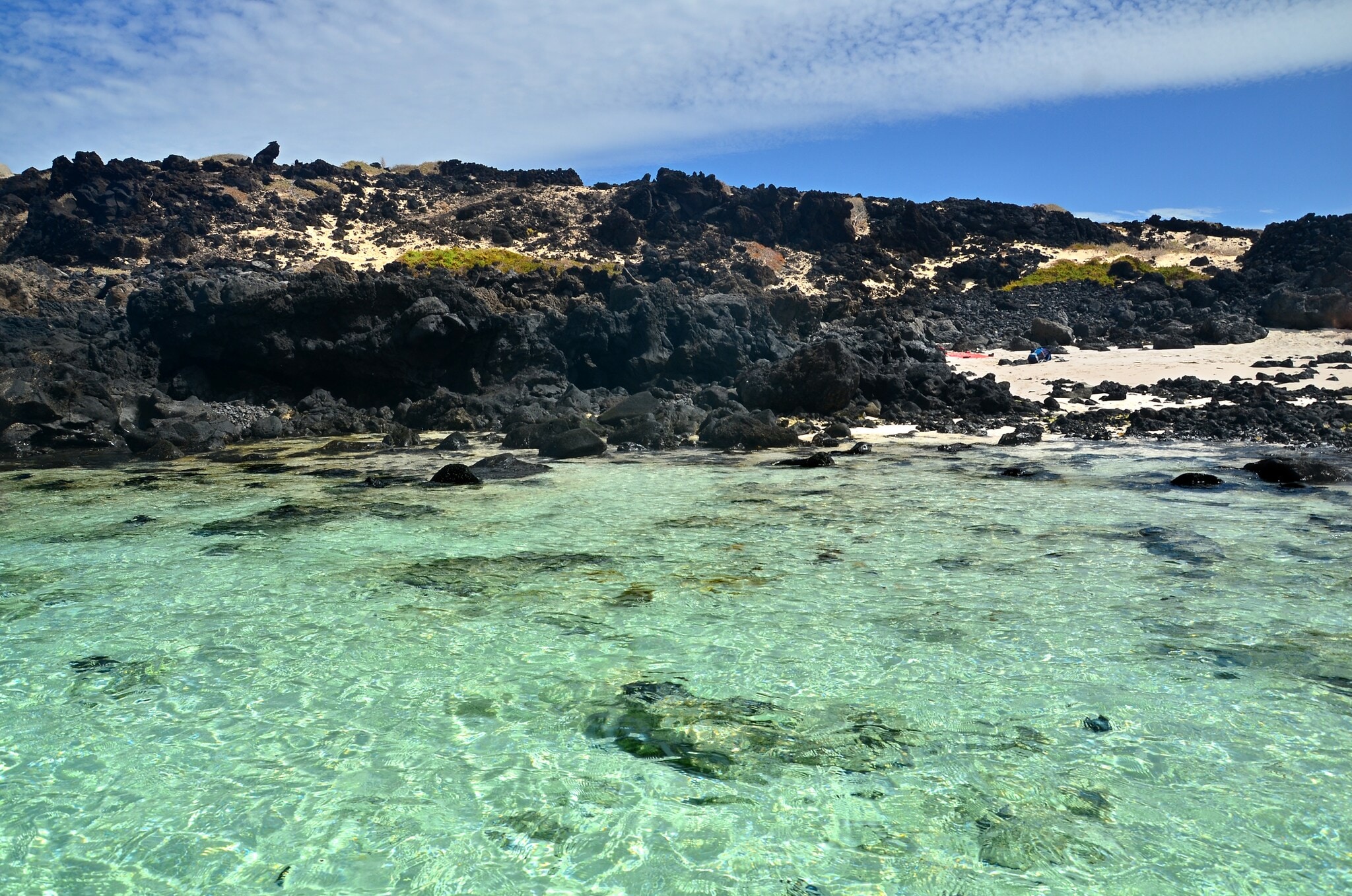 Blick auf den Strand von Caleton Blanco mit schwarzen Felsen und klarem Wasser Blick auf den Strand von Caleton Blanco mit schwarzen Felsen und klarem Wasser