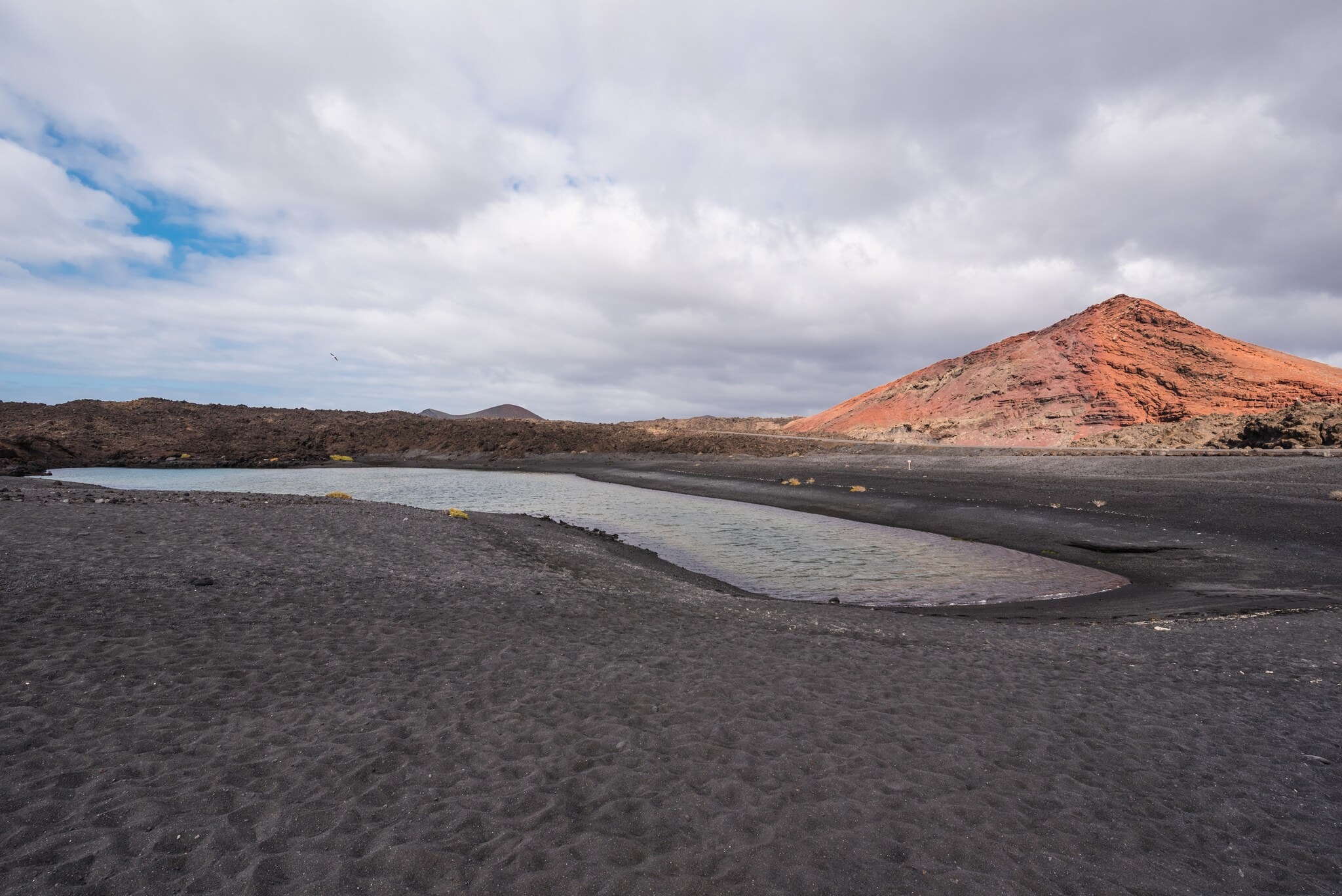 Schwarzer Sand und der Vulkankrater Montana Bermeja auf Lanzarote Schwarzer Sand und der Vulkankrater Montana Bermeja auf Lanzarote