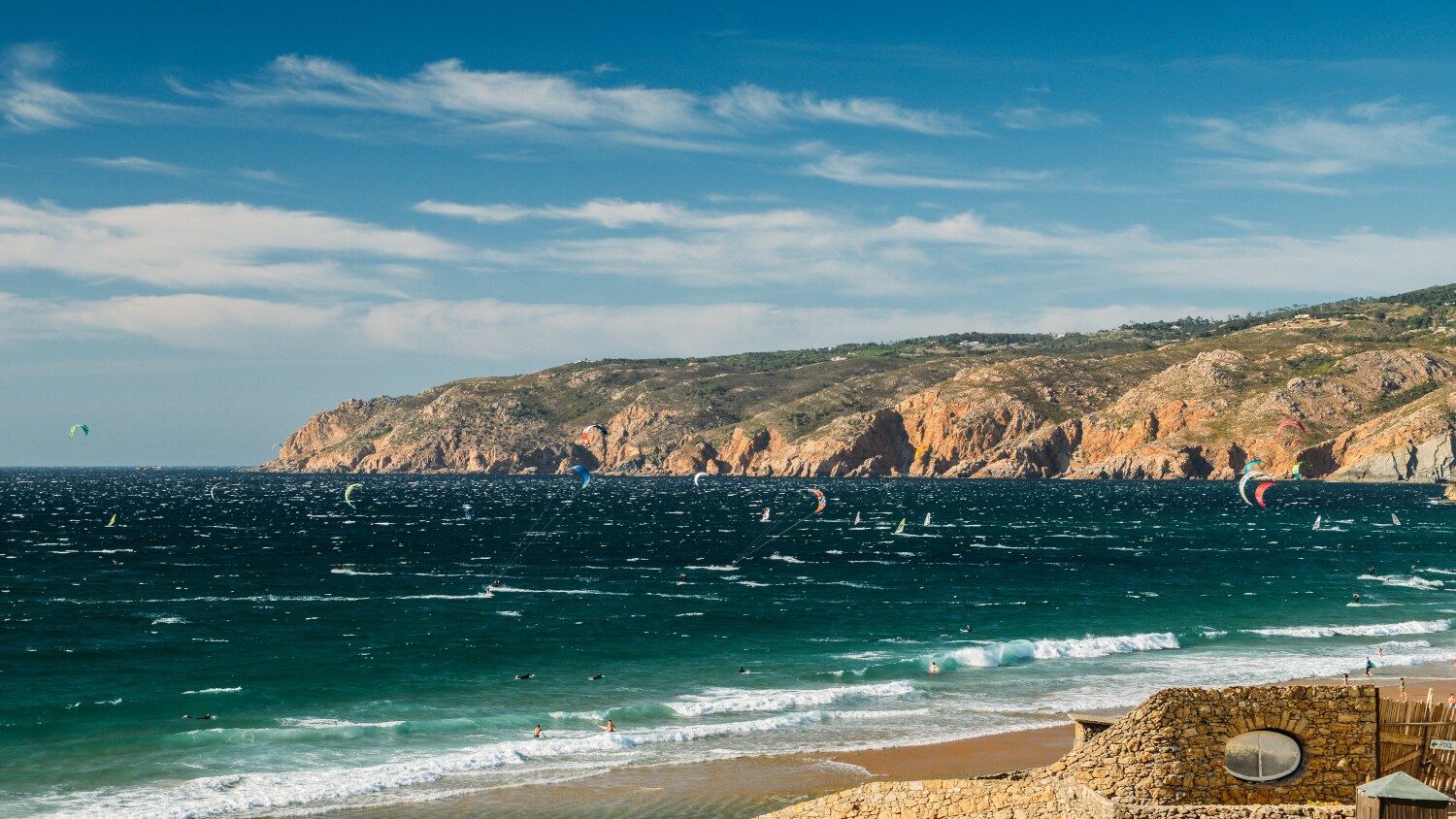 Eine felsige Meeresbucht mit Kitesurfenden im Wasser Eine felsige Meeresbucht mit Kitesurfenden im Wasser