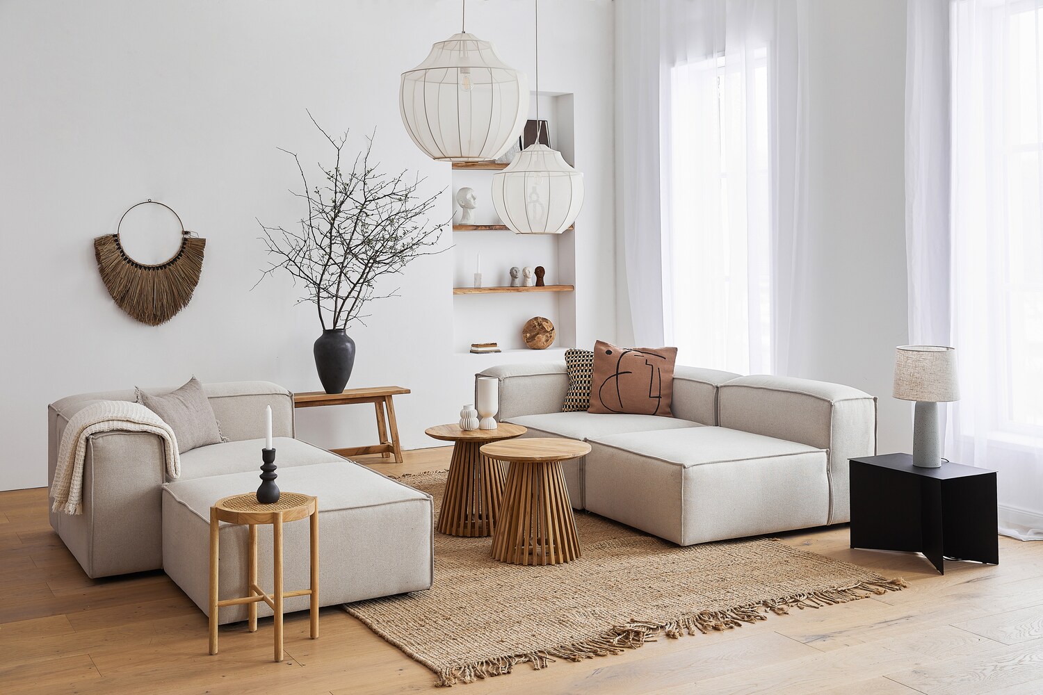 Ein lichtdurchflutetes, modernes Wohnzimmer im skandinavischen Design mit einer kubischen Sitzgruppe aus grauem Stoff und dekorativen Wohnaccessoires