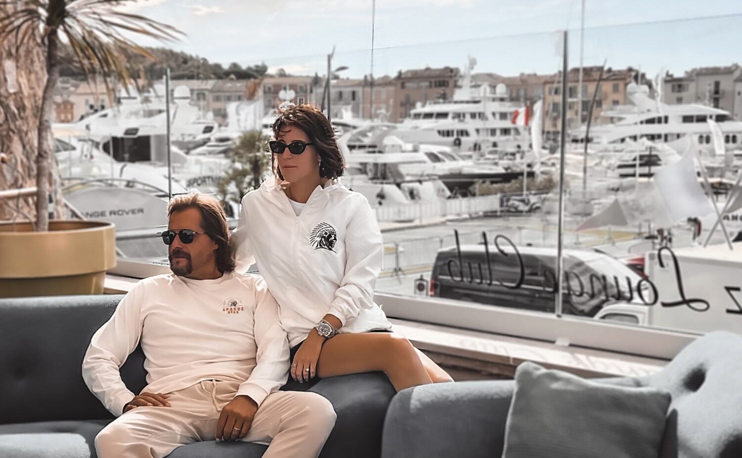 Ein Paar in sportlicher Kleidung sitzt an einem Yachthafen