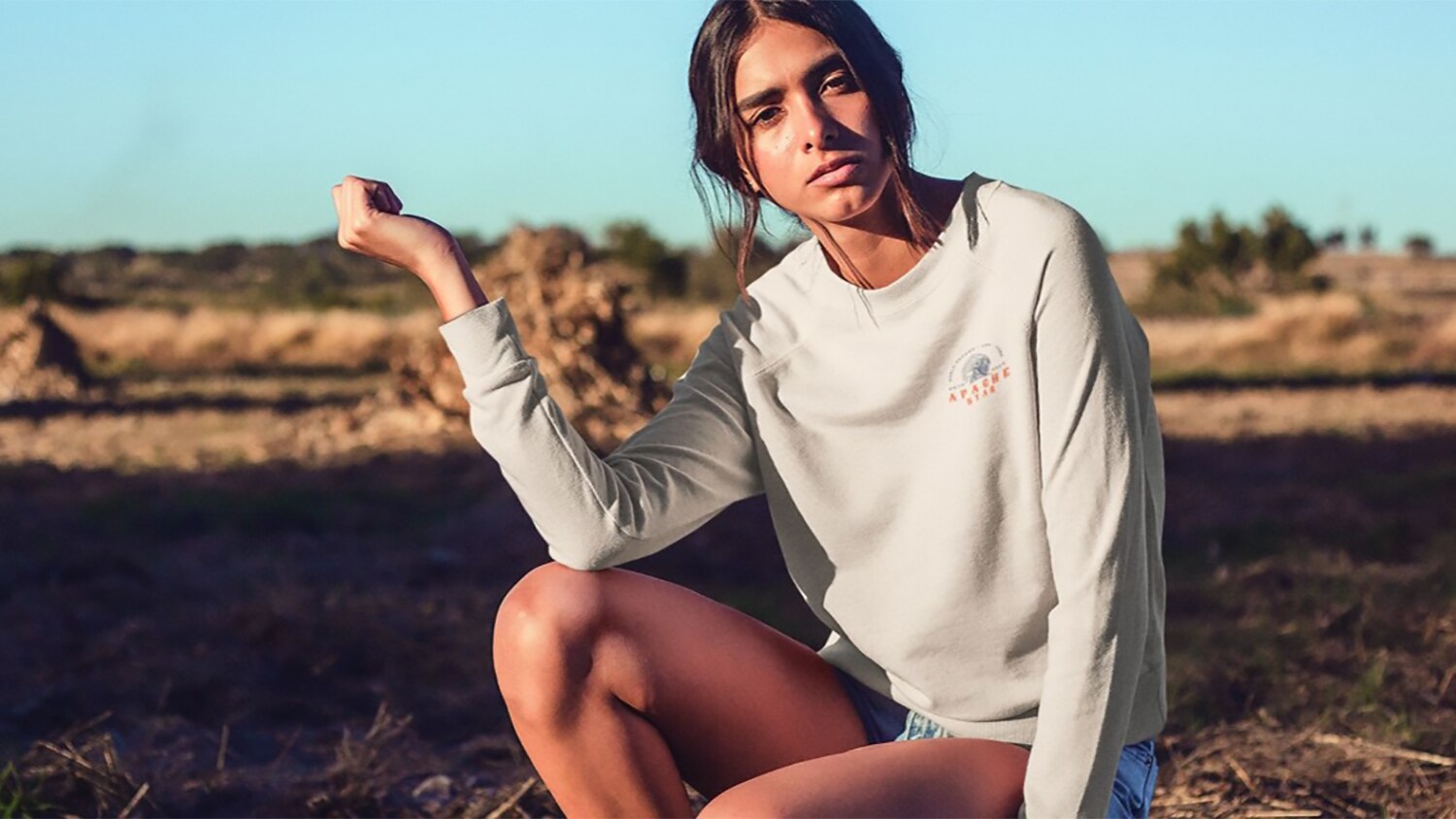 Eine junge Frau posiert in einem hellen Sweatshirt in der Natur