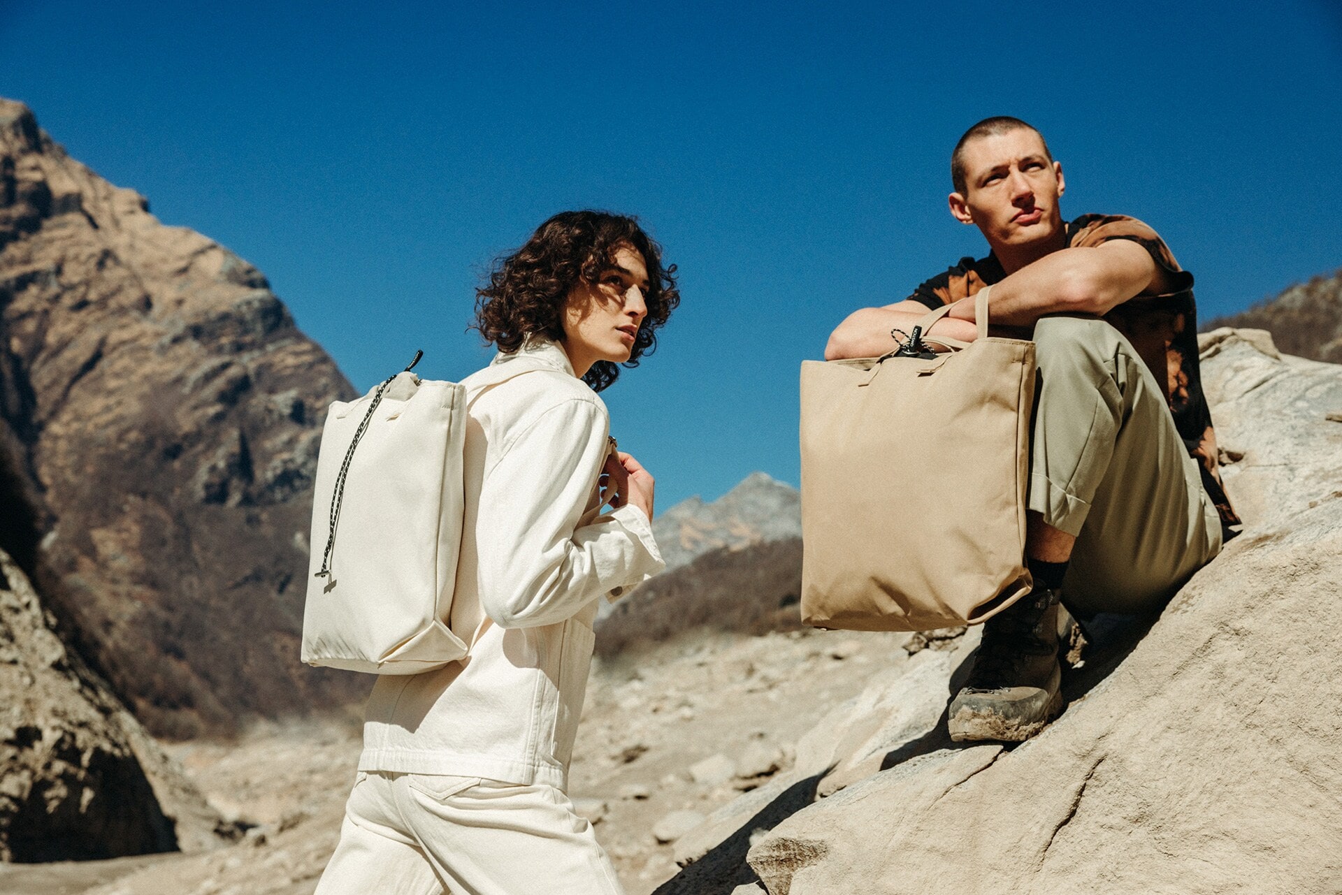 Zwei männliche Models sind in einer felsigen Umgebung unterwegs und setzen ihre Rucksäcke in Szene Zwei männliche Models sind in einer felsigen Umgebung unterwegs und setzen ihre Rucksäcke in Szene