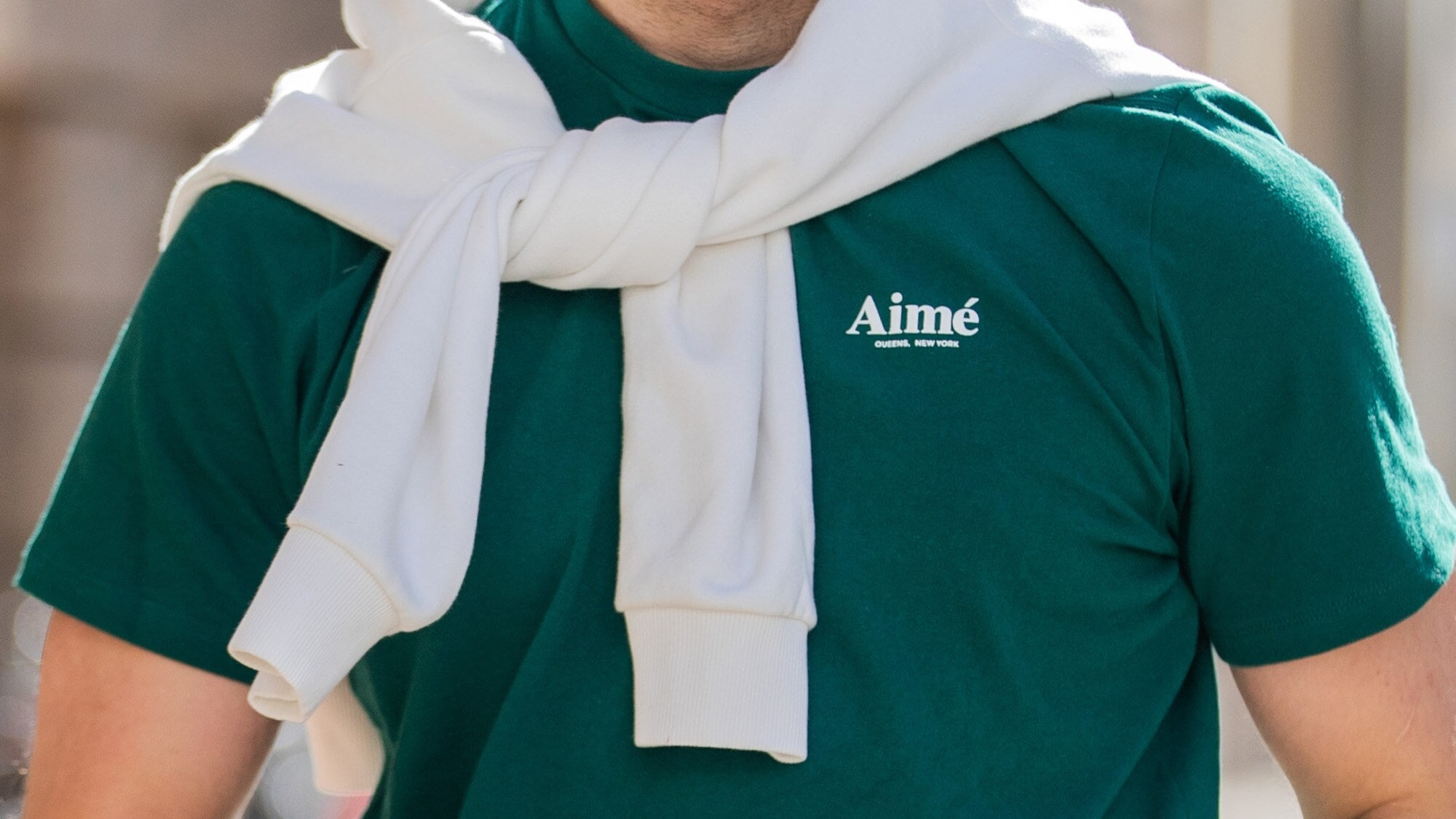 Oberkörper eines sportlichen Mannes in einem grünen T-Shirt mit dem Schriftzug der Marke Aimé Oberkörper eines sportlichen Mannes in einem grünen T-Shirt mit dem Schriftzug der Marke Aimé