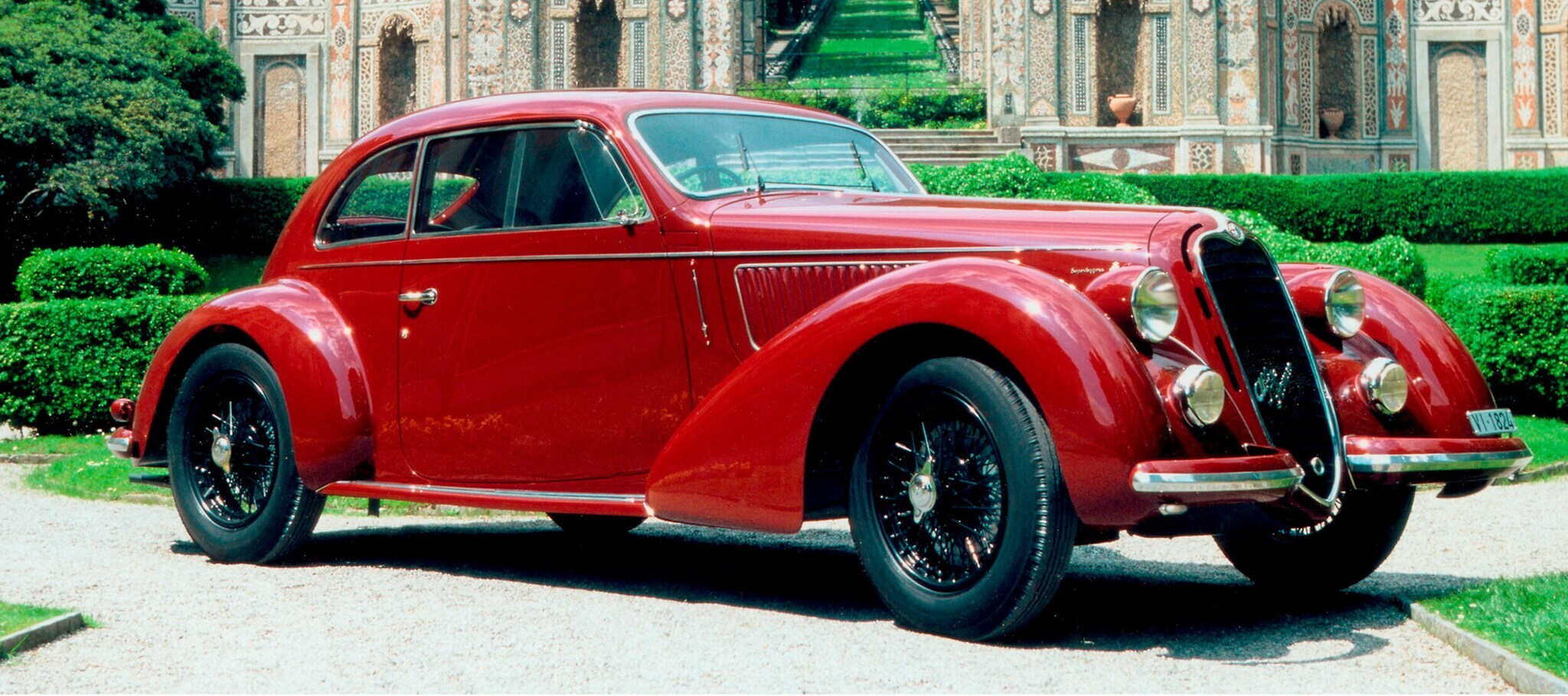 Ein roter Oldtimer vor einer Parkanlage Ein roter Oldtimer vor einer Parkanlage