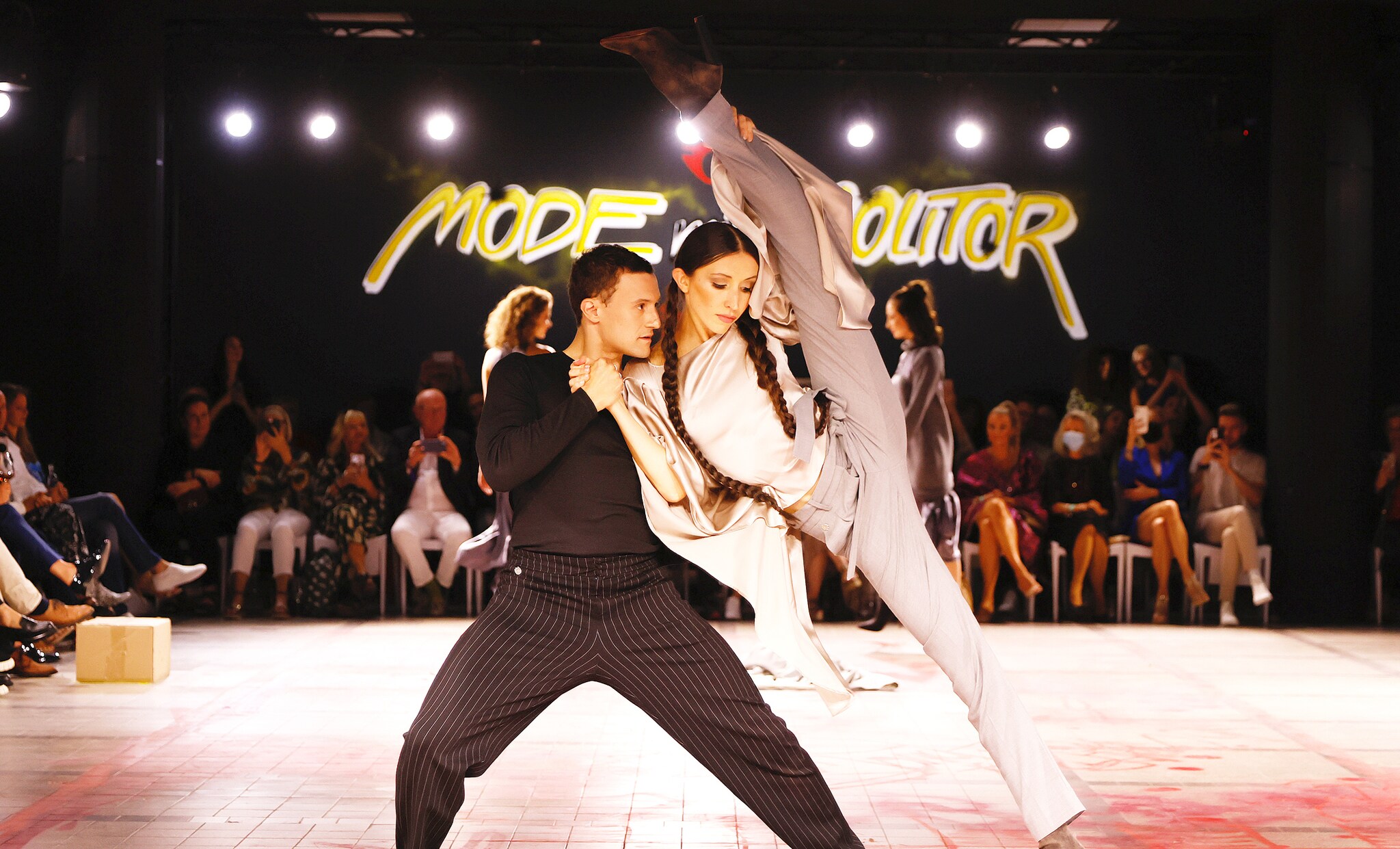 Ein Mann und eine Frau tanzend auf einem Runway vor Publikum