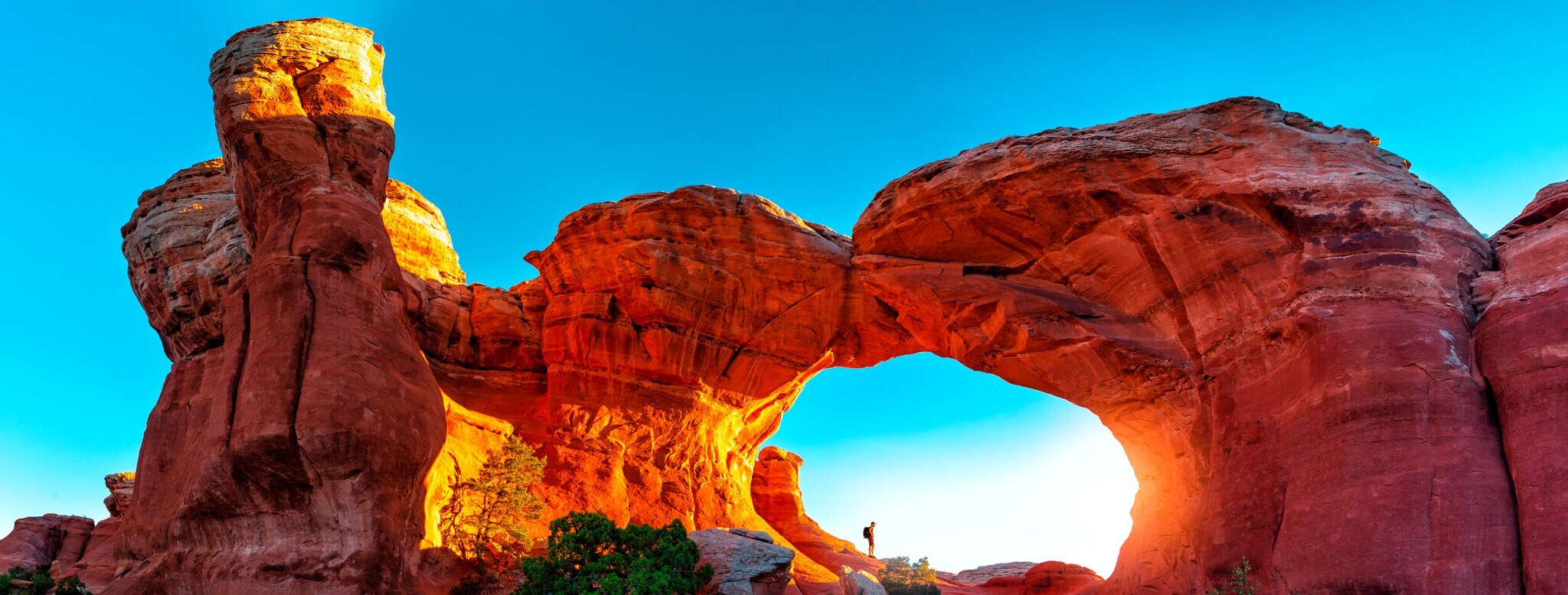 Ein Wanderer unter einem Felsbogen