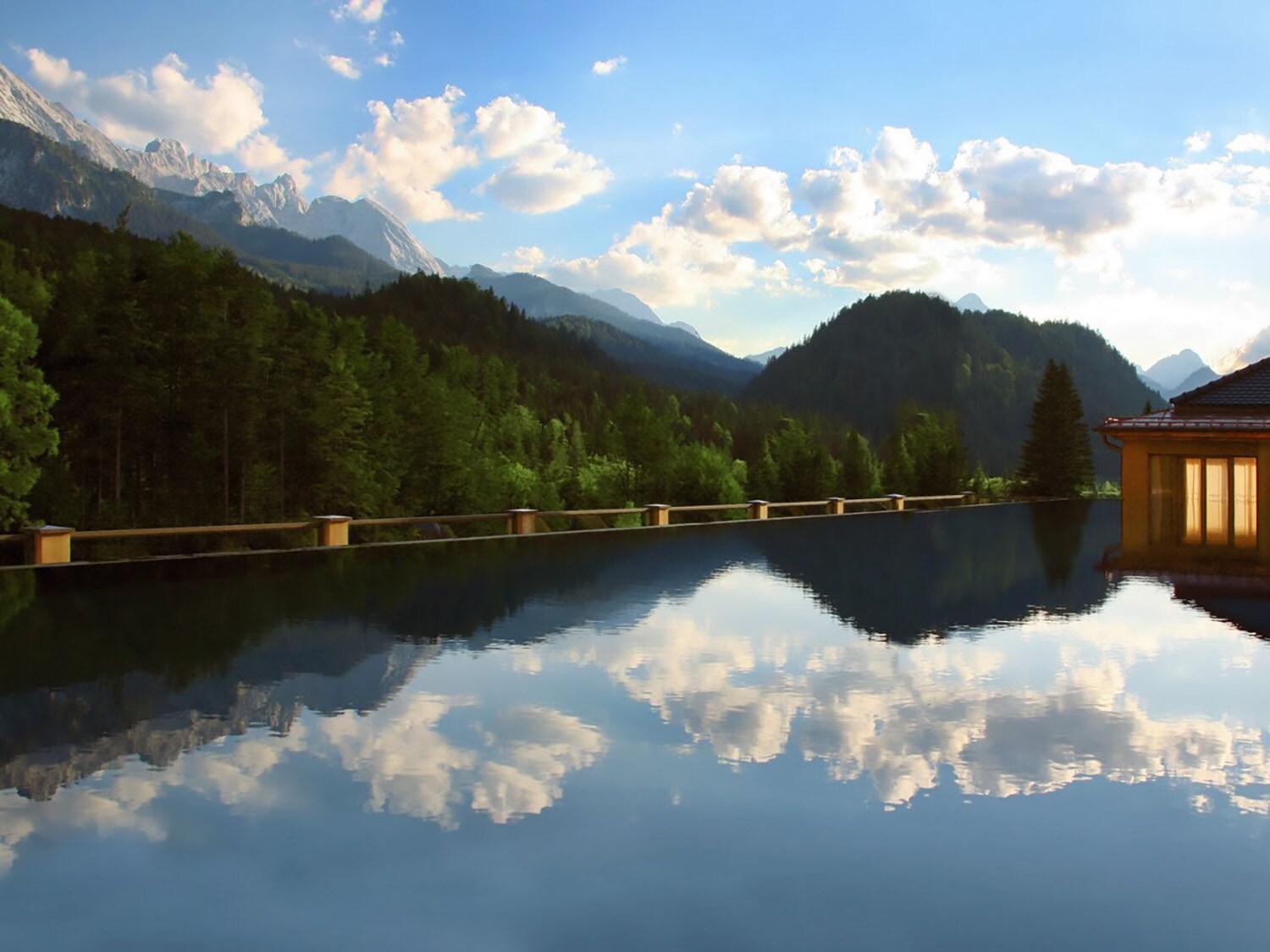 Ein großer Außenpool vor Wald- und Bergpanorama