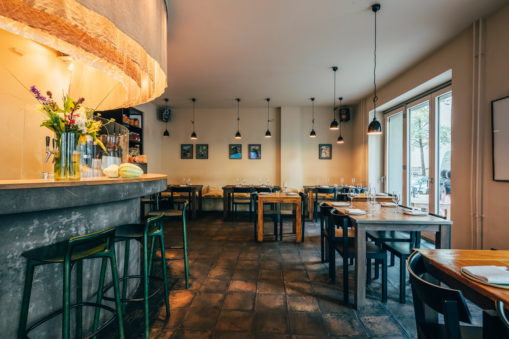 Innenraum eines modernen Restaurants mit einem Tresen und gedeckten Holztischen Innenraum eines modernen Restaurants mit einem Tresen und gedeckten Holztischen