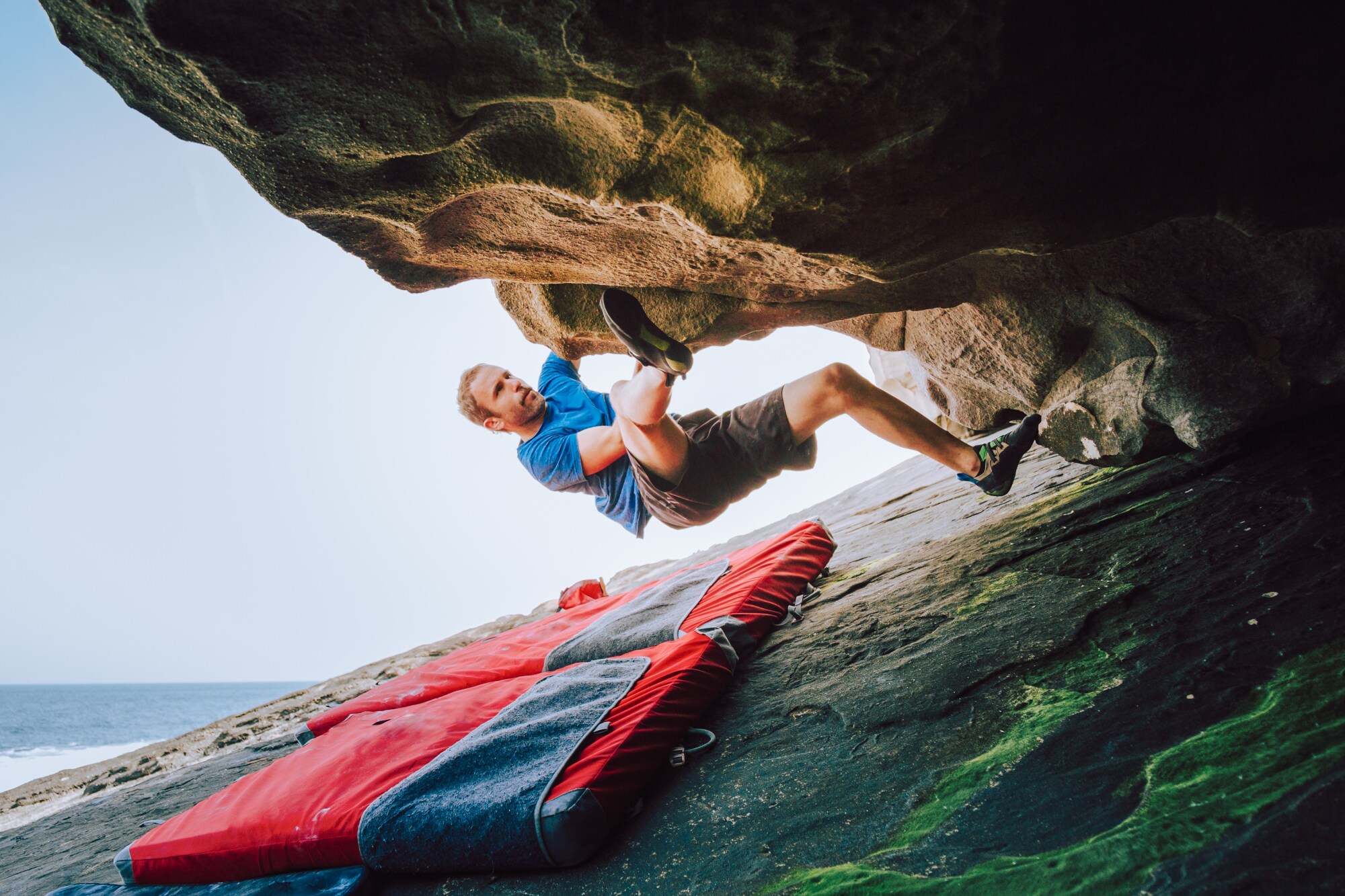 Ein Mann bouldert am Felsen, unter ihm liegt eine Matte