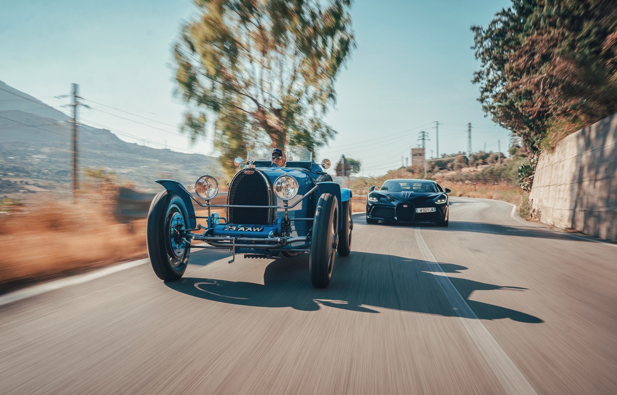 Ein Oldtimer und ein moderner Sportwagen auf einer Straße Ein Oldtimer und ein moderner Sportwagen auf einer Straße