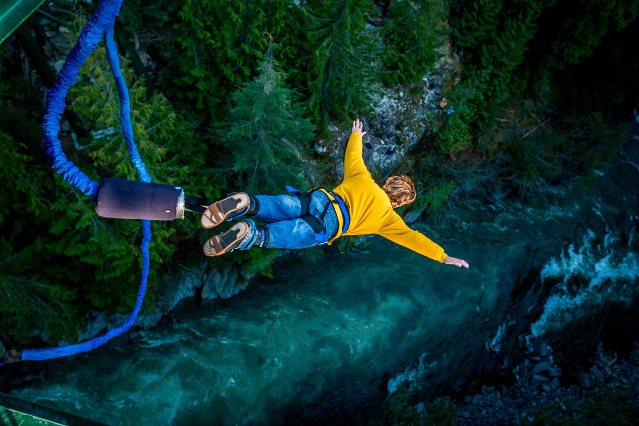 Ein Mann springt am Bungeeseil in die Tiefe, unter ihm fließt ein Fluss. Ein Mann springt am Bungeeseil in die Tiefe, unter ihm fließt ein Fluss.