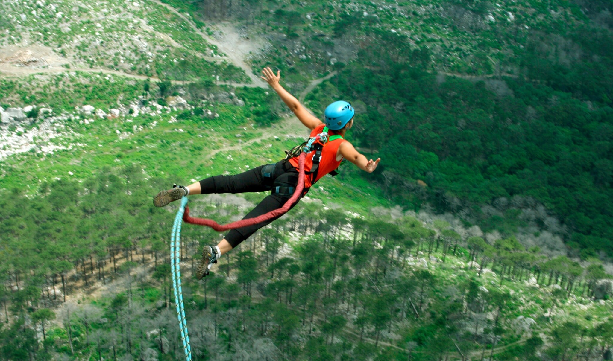 Eine Frau springt von einer Klippe am Bungeeseil in den Abgrund. Eine Frau springt von einer Klippe am Bungeeseil in den Abgrund.