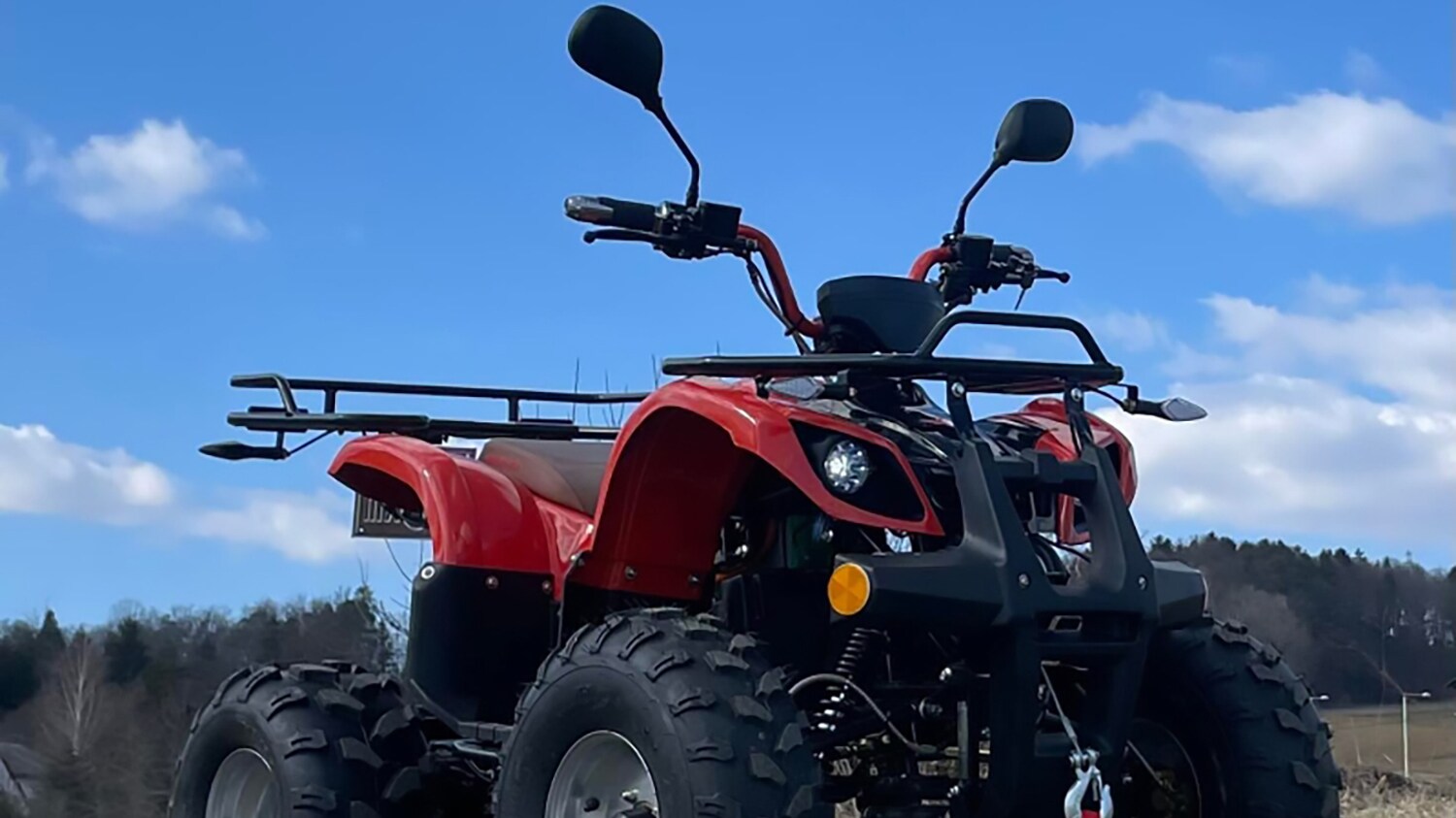 Ein rotes Quad steht auf unbefestigtem Gelände.