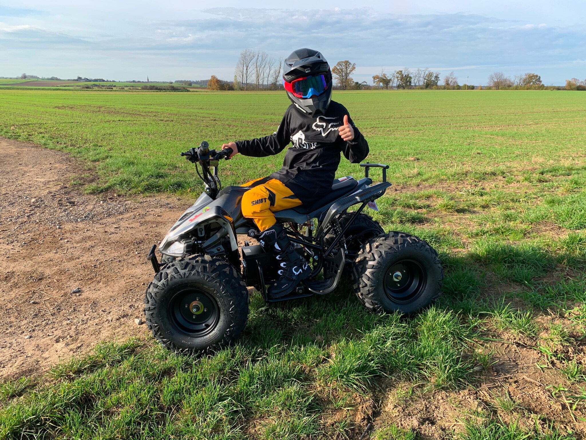 Ein Junge sitzt auf einem Quad, das auf einer Wiese steht. TR300