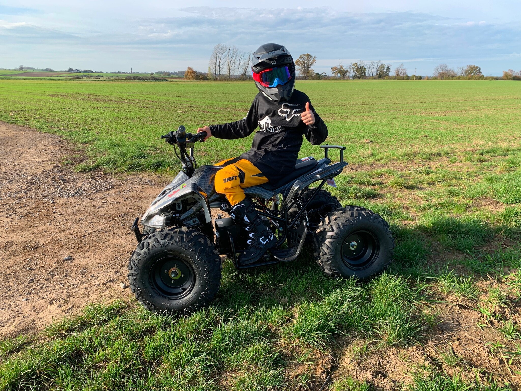 Ein Junge sitzt auf einem Quad, das auf einer Wiese steht. TR300 Ein Junge sitzt auf einem Quad, das auf einer Wiese steht. TR300