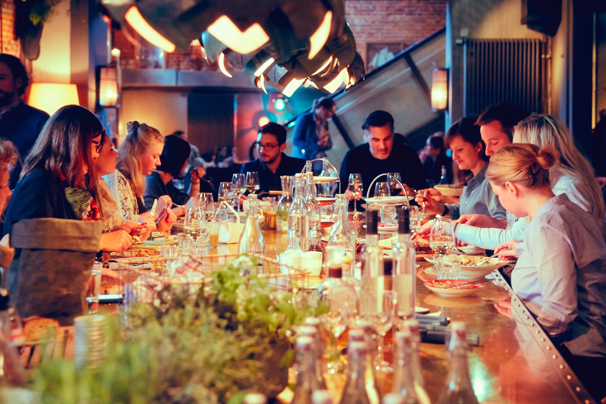 Eine große gesellige Menschengruppe sitzt an einem Tisch und isst zusammen.