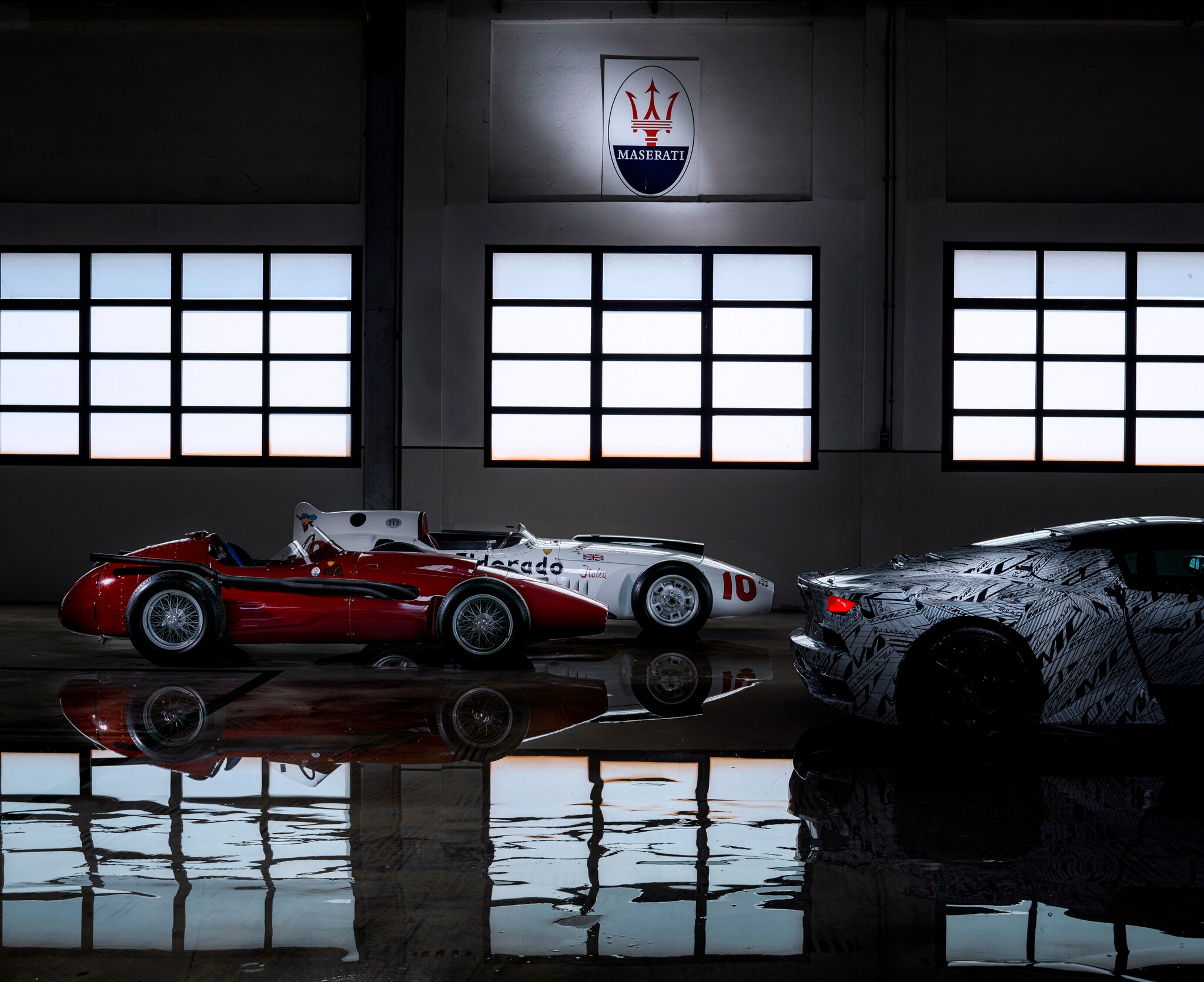 Zwei historische und ein moderner Sportwagen in einer Halle Zwei historische und ein moderner Sportwagen in einer Halle