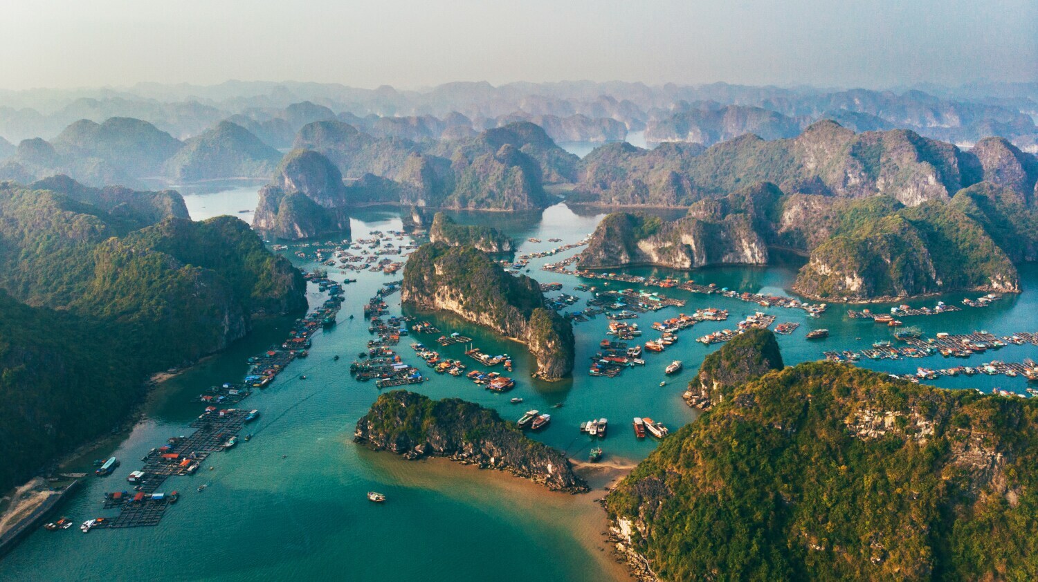 uftaufnahme des Naturweltwunders Halong-Bucht mit Booten, die im smaragdgrünen Wassern vor zahlreichen Inseln liegen Luftaufnahme des Naturweltwunders Halong-Bucht mit Booten, die im smaragdgrünen Wassern vor zahlreichen Inseln liegen
