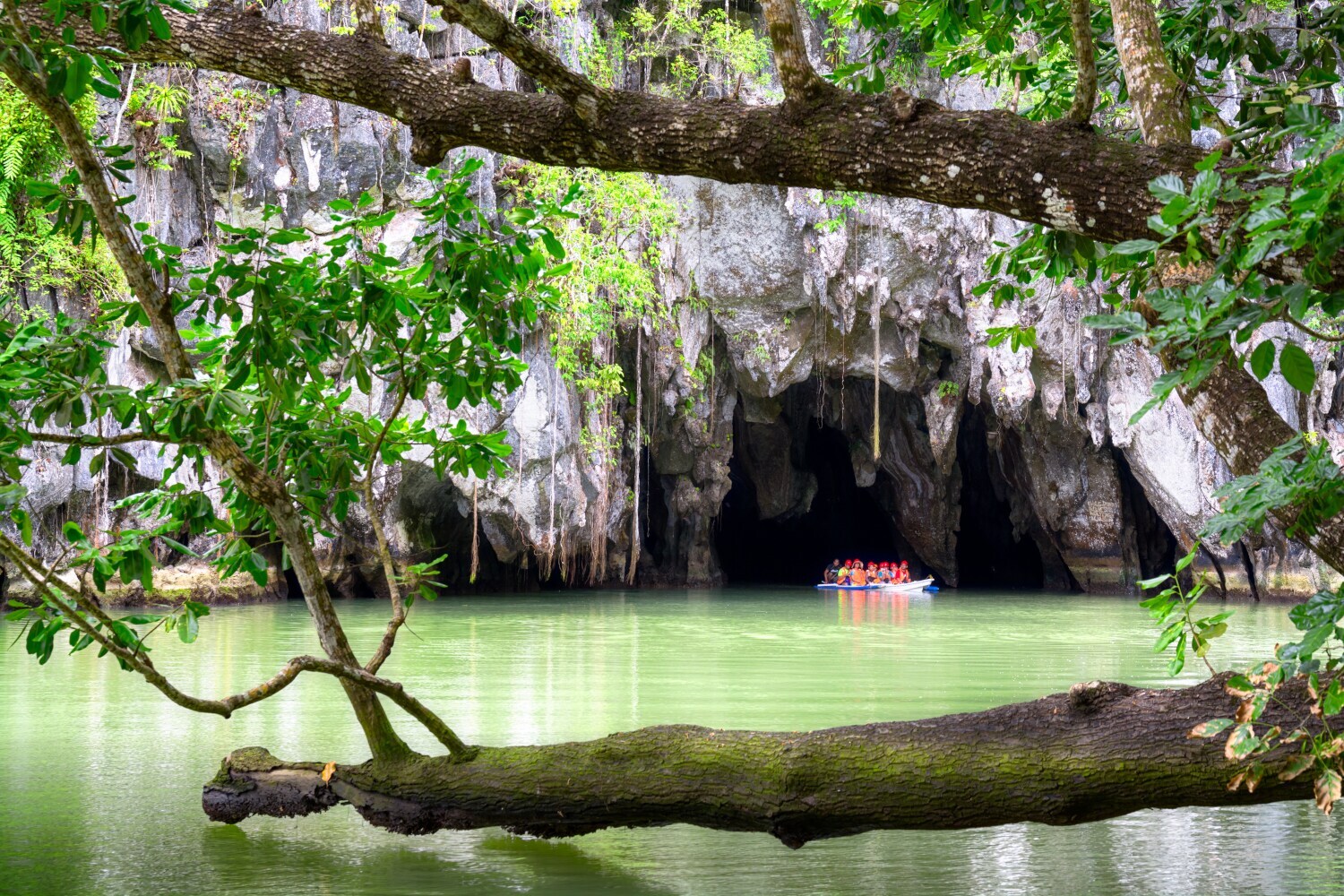 Ein Ausflugsboot fährt auf dem Wasser in eine Felsgrotte hinein Ein Ausflugsboot fährt auf dem Wasser in eine Felsgrotte hinein