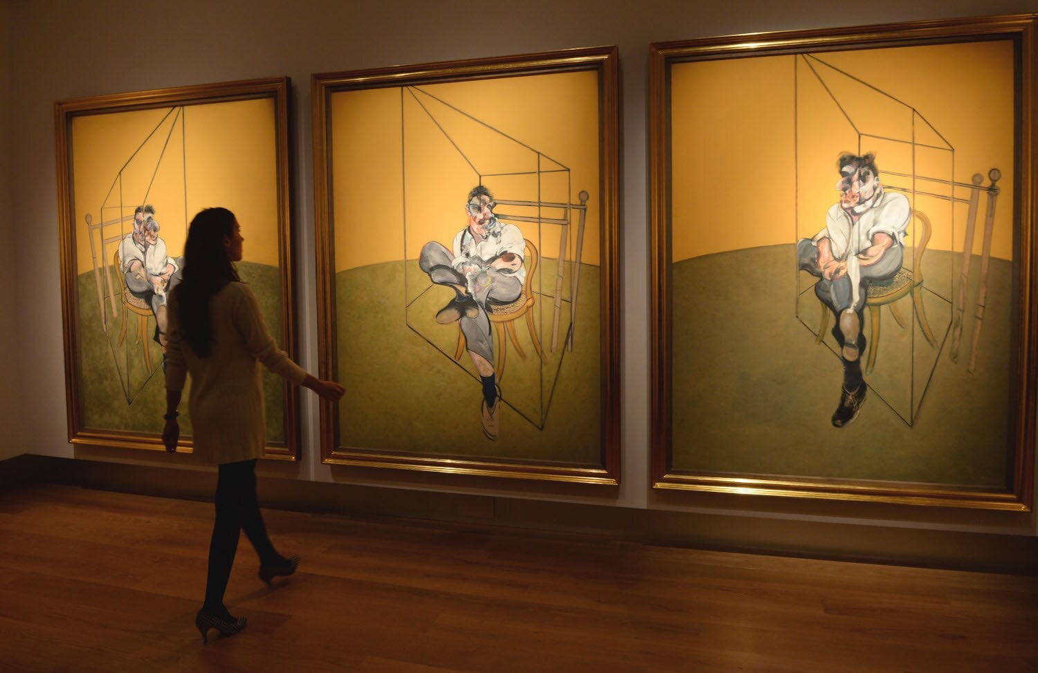 Eine Frau betrachtet drei Bilder von Francis Bacon in einem Museum Eine Frau betrachtet drei Bilder von Francis Bacon in einem Museum